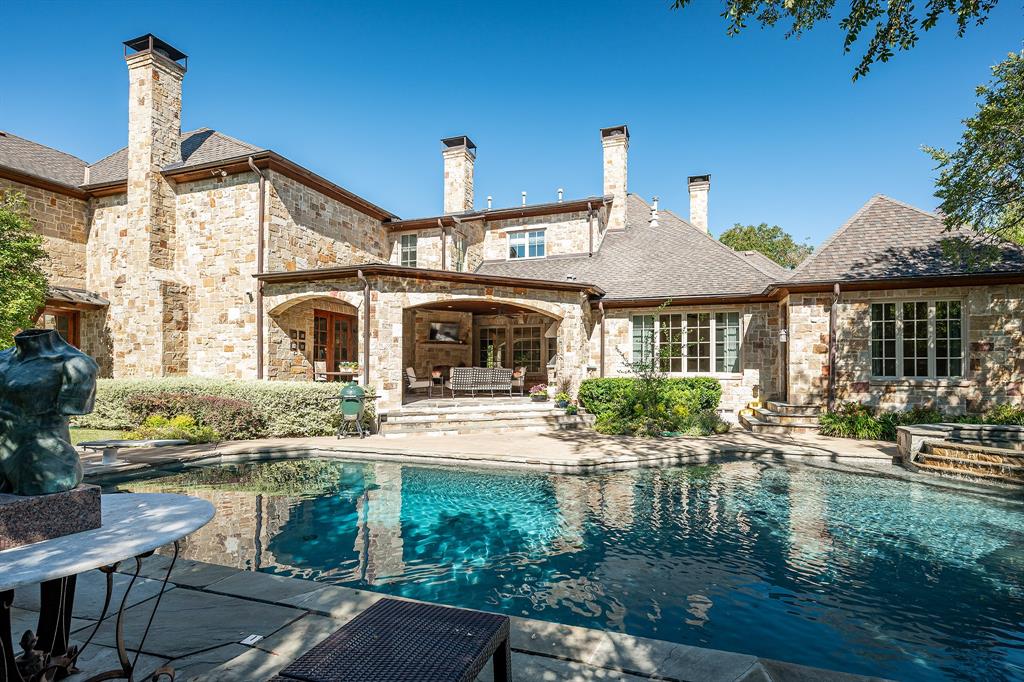 Extraordinary .5 acre Tuscan Villa in prestigious Bluffview. Structural warmth combines a bright airy palette in secluded residence featuring a blend of timeless architecture and natural beauty. Private residence of 7,553 square feet displays balance of Tuscan architecture, updated interior finishes.   Enter to rich hardwood floors, elegant arched walls, natural stone surfaces throughout. Heart of the home beats from stunning great room accented with handsome wood beams across soaring ceilings. A bar serves festive gatherings with the 200 bottle temperature controlled wine room. Open kitchen enjoys island, subzero, wolf appliances, twin dishwashers and causal dining bar. Counter tops finished with Taj Mahal leathered quartzite. The main level primary retreat is a sanctuary of quiet luxury that offering a tranquil escape from the energy of the day. Secreting it’s own sitting room gazing on the pool and yard. Primary bath boasts separate vanities and generous His-n-Her walk-in closets. No one will complain! Completing the first floor reveals handsome library-office and guest suite. Upstairs discover 4 bedroom suites creating comfort and privacy. Family, guests will enjoy the loft style game room, also a media room equipped with an 85” screen with surround sound. The versatile home hides a generous second floor exercise room complete with full bath, steam shower. Transitioning outdoors, the property reveals a resort style oasis framed by mature trees ensuring absolute seclusion. Covered outdoor living enjoys fireplace, generous seating, & outdoor kitchen; ideal for enjoying every season. Views of the stunning pool-spa center the large outdoor space. Gated drive, porte cache, and garage space for 3 cars complete this home.    You'll find a residential retreat designed for everyday comfort and unforgettable gatherings. An unmatched lifestyle of privacy and prestige awaits in one of Dallas’ most private and coveted neighborhoods.