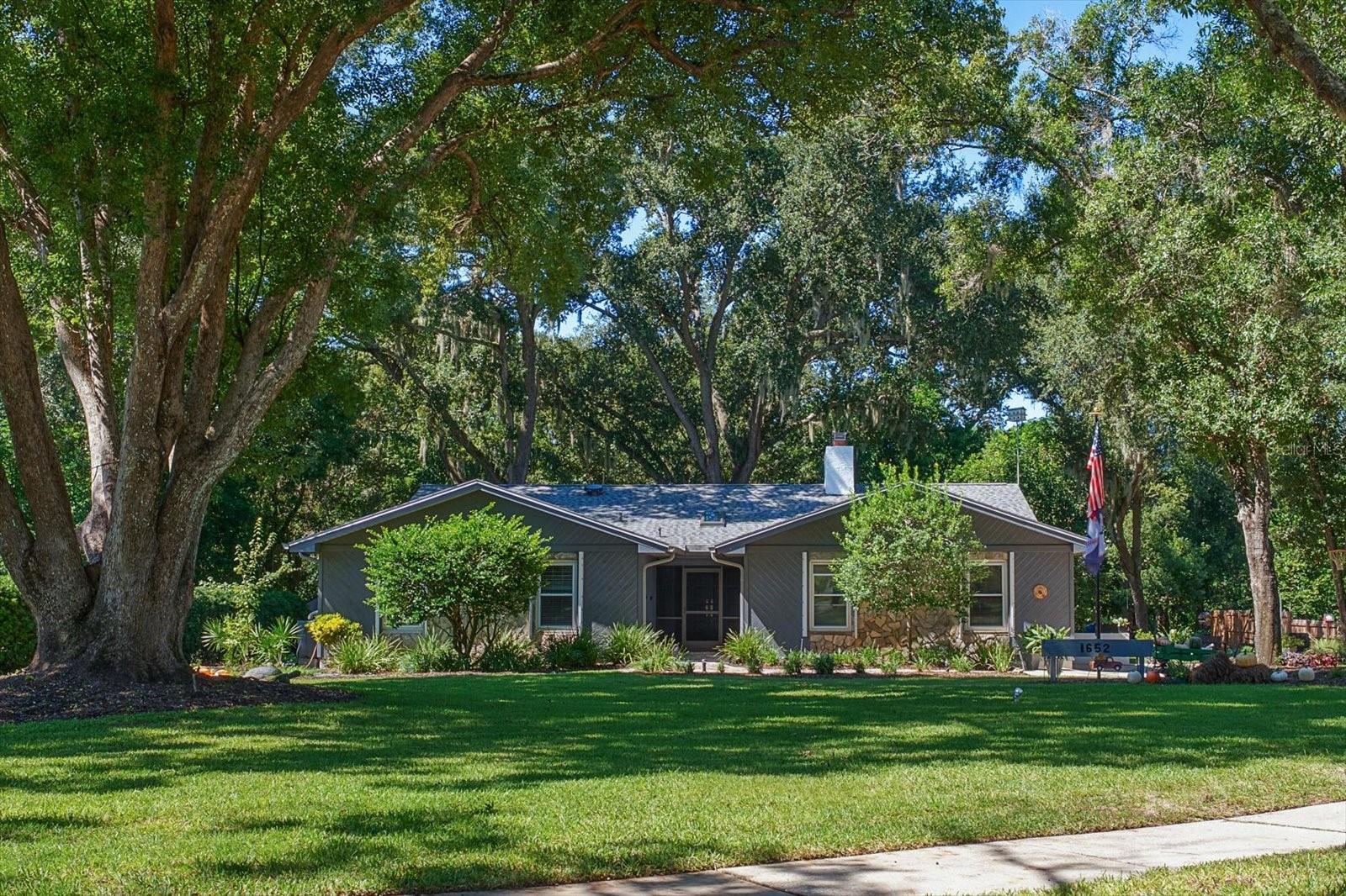 Virtually Staged. Some homes just have a way of making you feel welcome the moment you arrive. Tucked away on a quiet cul-de-sac and surrounded by majestic oaks, lush landscaping, and colorful flowering plants, this charming four-bedroom home offers the warmth, character, and sense of privacy that make a house truly special.  At the heart of the home is a spacious great room anchored by a beautiful wood-burning stone fireplace that creates a natural gathering place for holiday celebrations, cozy evenings, and lively get-togethers with friends and family. A convenient wet bar with a built-in wine rack makes entertaining effortless, while the thoughtfully renovated kitchen and bathrooms bring modern comfort and style without sacrificing the home's inviting personality. For an added touch of warmth, the primary bedroom features its own electric fireplace, creating a cozy retreat at the end of the day.  But perhaps the real magic lies just beyond the back door. Set on an expansive .80-acre lot with no rear neighbors, the backyard feels like your very own private park. Towering oaks provide a beautiful canopy, while the thoughtfully curated landscape features an abundance of flowering plants and lush greenery, carefully selected for both their beauty and their ability to thrive in Florida's climate. Birdsong fills the air, and cardinals and other feathered visitors are frequent guests. There's room for children to explore, dogs to run, and everyone to enjoy the simple pleasure of being outdoors. A screened patio and swim spa create the perfect setting for morning exercise, afternoon relaxation, or evenings spent unwinding in the peaceful surroundings. A dedicated well for irrigation helps keep the lush landscape thriving.  Beyond its undeniable charm, the home offers valuable practical improvements, including high-impact windows, a roof replaced in 2025, and an oversized garage providing generous space for vehicles and storage.  With its beautiful curb appeal, mature landscape, and timeless character, this is the kind of home that looks especially magical dressed up for the holidays and feels just as wonderful every other day of the year.  Warm, welcoming, and wonderfully private, this is a homemade for gathering, growing, and making memories.