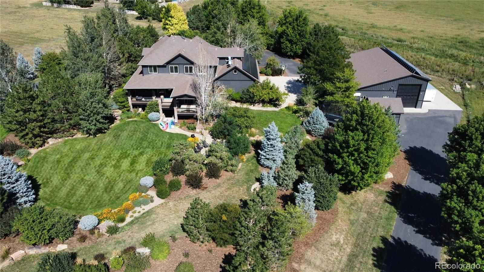 A RARE PROPERTY BLENDING LUXURY ACREAGE, MOUNTAIN VISTAS, AND A 10-CAR GARAGE. Experience elevated living on 3.11 acres, where thoughtful design, and breathtaking mountain views come together in a truly exceptional estate. This 6-bedroom, 5-bathroom residence is surrounded by over $800,000 in professionally designed landscaping, creating a serene, park-like setting complete with a water feature, fire pit, and fully lit grounds. Also, every tree and plant is supported by a comprehensive drip irrigation system.The home is perfectly positioned to capture panoramic views from the expansive wrap-around Trex deck, warmed by a stunning double-sided fireplace.. Inside, refined finishes include oak flooring, extensive custom built-in shelving, and a whole-home audio system with speakers in every room. A dedicated fitness room with mirrors adds a wellness-focused retreat, while the hot tub (included) is thoughtfully designed with proper drainage for ease of ownership.Designed for both luxury and functionality, the property features heated driveways, including a cobblestone main drive fully plumbed for heat, and fully paid-off solar, offering energy efficiency without compromise. The attached 3-car garage complements an extraordinary detached, fully finished and climate-controlled garage with room for a 50’ RV, collector grade automotive bays, 220V power, an office, and a bathroom. The RV bay includes a dedicated dump tied directly to septic, making this property ideal for RV enthusiasts or collectors.The entire yard is secured with an "Invisible" dog fence, while an additional acre provides endless possibilities—horses, a dirt bike track, or the option to build.This is a rare opportunity to own a meticulously designed estate that balances privacy, versatility, and high-end living—crafted for those who expect more, and built to accommodate it all.