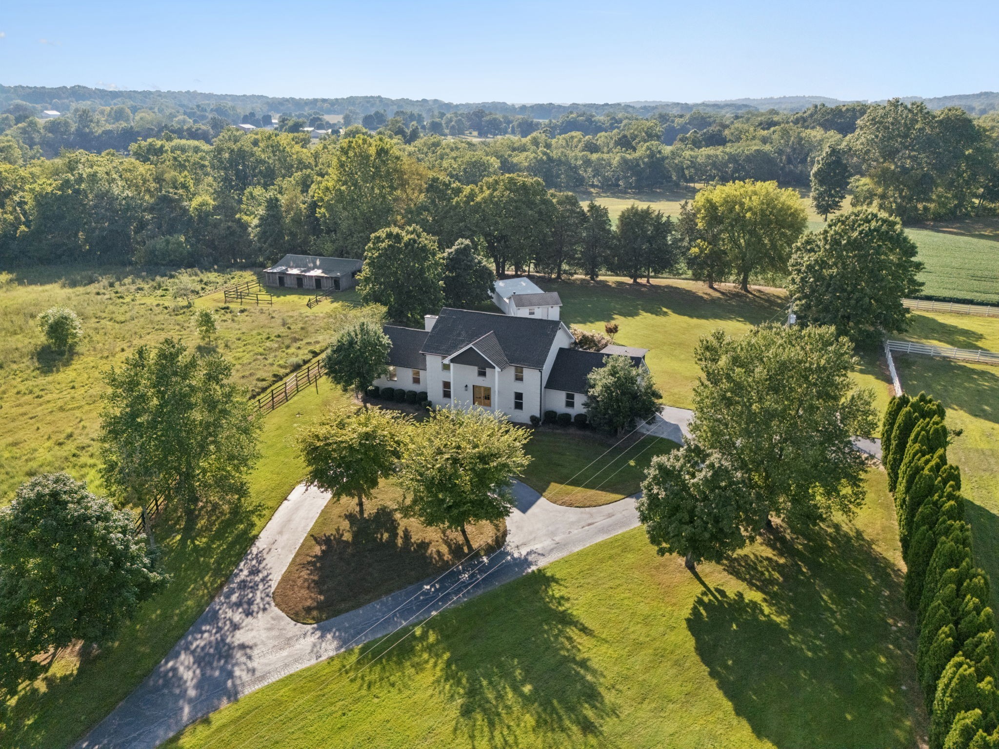 Discover the rare opportunity of owning this completely renovated 7.2 acre exceptional estate at 3935 Harmony Grove Road in picturesque Hopkinsville, KY. Your dream country retreat just a short drive to Hopkinsville or Lake Barkley, you can't beat this location! Walking in from the covered front porch you are greeted with an entry foyer leading to a vast open floor plan with exquisite views from every window. Encompassing approximately 3,440 square feet, this home is refined with top tier craftsmanship and modern luxury design. Featuring 5 spacious bedrooms and 3 luxurious bathrooms, it offers both space and style. Step into the gourmet kitchen, a chef's dream with designer lighting, custom cabinets, tile backsplash, granite countertops, farmhouse sink, a 6-burner gas range, double ovens and an expansive island complete with top-of-the-line stainless steel appliances. The open layout seamlessly connects to a living area adorned with an oversized fireplace and gleaming, sanded and finished hardwood floors. Retreat to the primary suite offering an expansive double walk-in closets, a stunningly renovated bathroom with dual vanity, separate freestanding bathtub and a beautifully tiled shower with frameless glass door, along with access to private deck vistas of the stunning 16 x 32 in-ground pool. The property boasts additional indulgences including a spacious utility room and tankless water heater. Spread across a generous 7 acres, the estate features four-board fencing ideally suited for horses, livestock, or farming with a picturesque pond, a barn with four stalls, and a five-bay utility shed. Enjoy the convenience of a long circular driveway, ample parking and a two car garage. Whether entertaining or relaxing, this home is a sanctuary where every detail has been thoughtfully designed to offer the very best in luxury living. This private estate is truly one of a kind in every way. Don't miss the opportunity to own a piece of paradise in the heart of Southwestern KY.