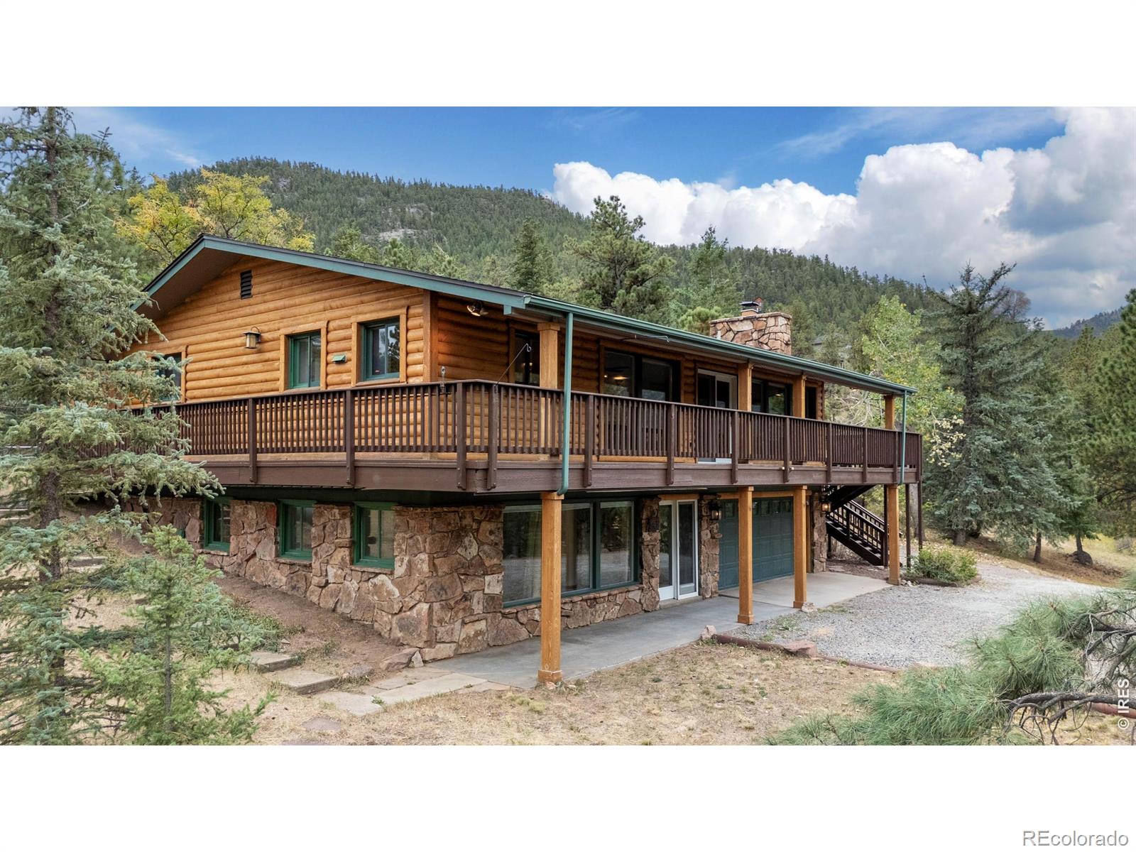 A small private hiking trail and a hot tub make a very good pair. At 42 Ottawa Court, you can spend the afternoon exploring your own 3.48 acres and the evening soaking beneath the stars. Meadow, pines and dramatic rock outcroppings give the land its character, with a trail leading to broad views of the surrounding national forest. Pull a chair into the sunshine or watch a storm cross the mountains from the shelter of the covered deck. The log-sided home has the windows this setting deserves, keeping the scenery in sight from the generous, open living area. A substantial stone fireplace makes a snowy afternoon something to look forward to. Recent improvements include fresh interior paint, a new furnace and water heater, and a roof replaced just a year ago. The home offers 2,070 square feet, three bedrooms and two baths, with two bedrooms on the main floor and a third downstairs. A fenced area accommodates the dog, while the oversized attached two-car garage has extra storage for tools, hiking boots and the rest of your mountain gear. Pinewood Springs puts Lyons in one direction and Estes Park in the other, with restaurants, shops and live music a drive away. Community water and maintained roads add practical appeal, and Boulder and Longmont are within commuting reach. A morning on your own trail doesn't have to wait for the weekend.
