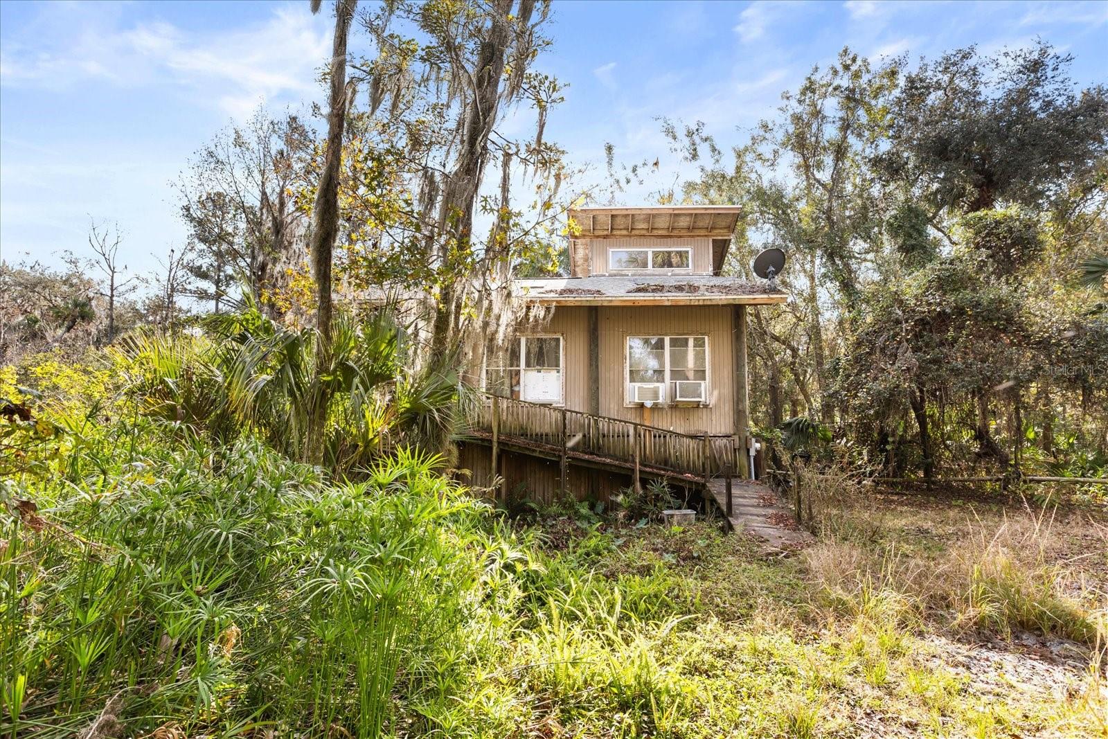 Under contract-accepting backup offers. A RARE FIND! Nestled on 10 ACRES in Geneva’s Cochran Forest in Seminole County, this property offers unmatched privacy, flexibility, and opportunity—ideal for a private family compound or custom estate. Located within one of Florida’s top school districts and inside the rural boundary, this land is protected from dense future development, ensuring your seclusion remains intact.Surrounded by mature trees and backing directly to the Black Hammock Wilderness Area, the property offers no rear neighbors and a true Old Florida setting. The majority of the land is high and dry, making it well-suited for multiple uses, including residential, agricultural, or equestrian living. Due to the lot size, the property allows for up to four dwellings, offering the rare ability to build a primary residence along with guest homes or mother-in-law apartments.A rustic rural stilt home currently sits on the property, featuring 1 bedroom and 1 bathroom—perfect for living on-site while constructing your custom dream home. Infrastructure is already in place with three power meters, an on-site transformer box for future expansion, and a new well filtration system installed June 2024.Animal lovers will appreciate the poured concrete floor pole barn, detached barn, and stable with potential for horse paddocks. With no HOA, you’re free to bring horses, goats, chickens, plant gardens, and fully embrace country living. Cochran Forest, a government-protected preserve dedicated to equestrian trails and hiking, lies directly behind the property—an exceptional extension of your backyard.If you’re seeking a private, rural retreat with endless potential in a protected natural setting, this is the real Florida—peaceful, secluded, and truly one of a kind.