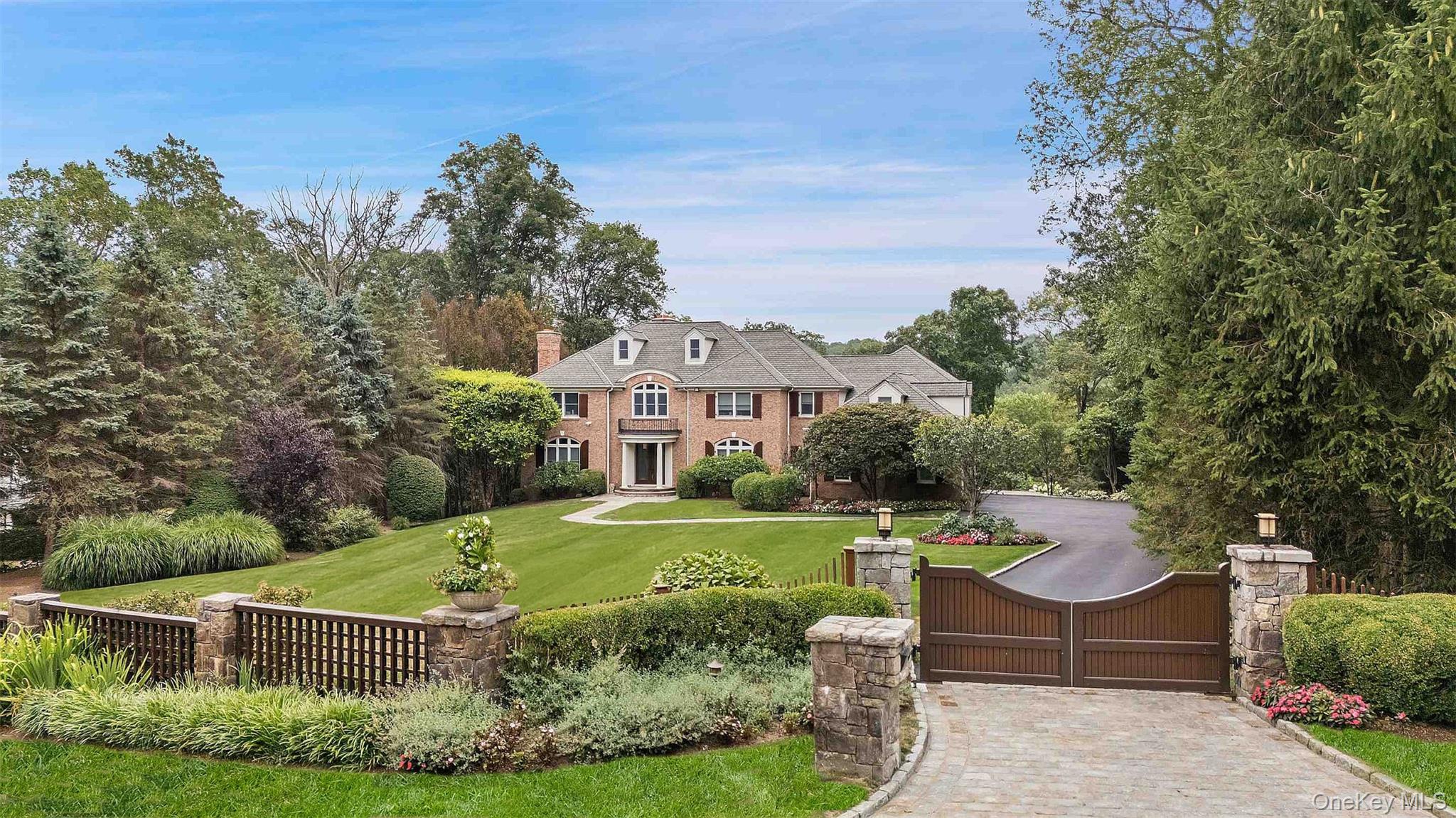 Gracious Brick Georgian Colonial, nestled on 2 resort-like acres with a gated drive, was designed for an elevated living experience. Throughout the home are generously sized spaces that seamlessly combine a sophisticated floorplan, perfect for everyday functionality, with tasteful finishes.  The two-story grand foyer, anchored by a sweeping staircase and bathed in natural light, creates a striking first impression. The chef’s kitchen is a showstopper with exposed wood beams, custom cabinetry, high-end appliances, center island and adjacent service pantry with ample storage. An elegant arched opening leads you to the family room with stone fireplace and French doors out to an expansive deck. A warm home office with custom paneling and fireplace offers an additional space for work or study. The upper level boasts a primary suite, the crown jewel of this home, featuring tray ceilings, a dressing room with center island, and a truly magnificent spa-inspired bathroom complete with a sauna, soaking tub, and walk-in shower. 3 additional ensuite bedrooms, plus a bonus room complete this level.  The lower level is for entertaining with a media room, bar, state-of-the-art gym, and a spectacular 3-season porch that leads to the patio and pool area. Outdoors showcases specimen plantings, stone walls, a heated Gunite pool and outdoor kitchen, perfect for relaxation and entertainment. Minutes to Armonk town center, schools and highways. 50 minutes to NYC.