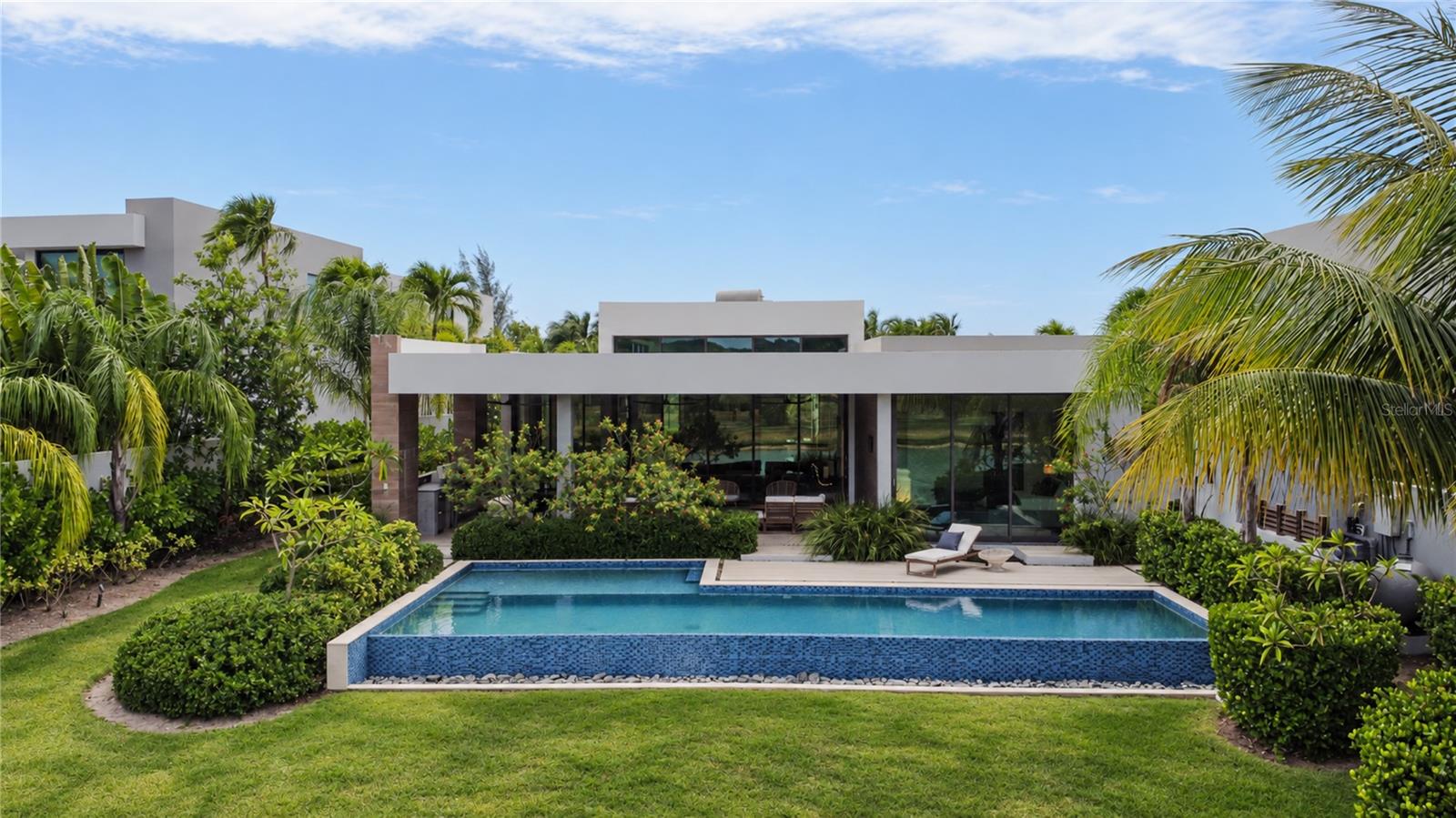 5 Salt Lane is located in “The Estates” section of The Isles at Dorado Beach, known for its larger lots and floorplans, greater privacy, phenomenal water views and a consistent breeze. As you enter the property, there is an immediate sense of space. Nearly 15-foot ceilings give the main living space a wonderful sense of volume, while the single-level layout creates an easy, natural flow from one room to the next. The living and dining areas flow into the kitchen, and an entire wall of glass doors disappears into the walls, allowing the expansive living area to open completely toward the pool and the landscape beyond.  The bedrooms are spread throughout the home, creating little pockets of privacy and making the house feel much more intimate. The primary suite opens directly to the outdoors, creating a private connection to the pool. Its bathroom feels like a private retreat, with a freestanding tub, four showerheads, double vanities, walk-in closet, and a double outdoor shower tucked away in complete privacy.But it is the backyard that sets this home apart.  The pool seems to disappear into the landscape, and the lake begins just beyond the lawn. There are no homes directly behind you, just water, mountains, open space and sky. The prevailing breeze moves in from the east, and with nothing blocking the property’s exposure, it finds its way through the outdoor spaces throughout the day.This is a house made for living outside. Long lunches become afternoon swims. Evenings naturally move toward the outdoor kitchen and pool. And then, as the sun begins to set, everything changes. The sky turns shades of pink and orange, the light softens, and the house takes on an entirely different feeling, a feeling that you have arrived somewhere truly special. And those are the moments that are priceless. Built in 2022 with four ensuite bedrooms, a heated saltwater infinity-edge pool, outdoor kitchen, full backup generator, 900-gallon water cistern, water softener system, solar water heater and two-car garage with golf cart space and a Tesla charger, the home offers every modern convenience.  Beautifully furnished and offered with furniture negotiable.