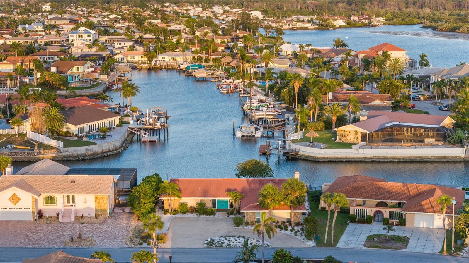 SELLER MOTIVATED!!  Experience coastal living at its finest in this beautifully renovated waterfront home, nestled in the highly sought-after Gulf Harbors community. Enjoy direct access to the Intracoastal Waterway and Gulf—perfect for boating, beach days, and sunset views right from your backyard. Sitting at a rare 13 feet of elevation, the property remained virtually untouched by recent storms and includes an elevation certificate and assumable flood insurance for added peace of mind. Along 85 feet of pristine seawall, a wide, deep-water canal offers seamless Gulf access—ideal for boating enthusiasts. Inside, the home showcases high-end updates and features throughout. New flooring over a waterproof membrane, Frigidaire appliances, a Sharp microwave drawer, custom cabinetry, and elegant quartzite countertops elevate the kitchen and baths. Details like Moen fixtures, modern tilework, craftsman-style doors, a marble-surround wood-burning fireplace, and upgraded LED lighting with dimmers add style and comfort. Impact windows, sliding doors, and a reinforced garage door enhance safety and efficiency. Mechanical upgrades include 2022 HVAC systems, a hybrid water heater that cools the garage, new garage mechanics with wireless opener, a dedicated electrical sub-panel, and a full water softener/treatment system. Landscape lighting enhances the home’s curb appeal after dark.The outdoor space is built for waterfront living: power is installed for a future boat lift, ALREADY INCLUDED are components for a 10,000 lb lift and Jet Ski components. Plans for New Dock/Lift available.  Fabulous OVERSIZED floating dock with two gangways and composite decking is perfect for kayaking or guest docking. A 4-hole putting green adds backyard fun, while drip irrigation keeps the landscaping low-maintenance and lush. Just minutes from downtown New Port Richey in a golf cart-friendly neighborhood, residents also enjoy exclusive access to the Gulf Harbors Private Beach Club—adding even more to this turnkey waterfront retreat.