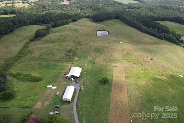 61-acre farm in Norwood, NC featuring a finished condo-style living space inside the main barn at 560 sq ft. 52'x65' working barn includes a cattle alley, headgate/squeeze chute with scales, and LED lighting. 27'x60' tractor/hay barn and new grain silo on site. Fenced pastures with multiple gates for rotational grazing; left pasture (approx. 8 acres) equipped with all-around fencing—0.50-acre pond located centrally on property. Well provides water to 4 self-watering stations and 2 hay feeders. The rear property line follows South Ugly Creek. The versatile layout is ideal for cattle or can be easily converted for equestrian use. Multiple potential home sites offer scenic views—a great opportunity for livestock, recreation, or future development.