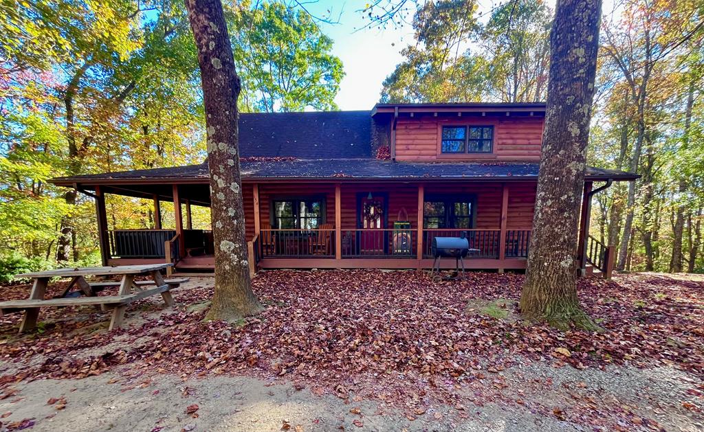 This AMAZING log cabin sits on 2 beautiful acres, .3 miles off of the Blue Ridge Pkwy, and is nestled in a canopy of mature trees and secluded bliss. Outside you'll find a fire pit, and circle driveway. Over half of the perimeter of the cabin is a 768 sq ft covered porch that houses a huge porch swing/bed, a hot tub, and lots of outside lighting. Around the back of the deck you'll enjoy a beautiful Mountain View. Open the front door into the great room boasting a 2-story cathedral ceiling, rock fireplace, hardwood flooring, and lots of windows for natural light. Beyond the great room you will find the dining room, and a well appointed kitchen with all of the extras. French doors lead back onto the fabulous deck. Down the hall you'll find the first floor bath, complete with a jetted tub, and a huge master bedroom complete with a full sitting area. Upstairs, look over the loft balcony to the great room below. The loft could be used for an extra bedroom, or office space, but is currently a den/game room. There are also 2 more large bedrooms and another full bath upstairs. There is a full-sized DRY basement that's perfect for storage, and where you'll find the laundry area. The cabin is located less than a 1/2 mile to the Music Center where there's always entertainment. Just a short drive puts you in downtown Galax where there are great shops and restaurants and festivals cruise-ins, and parades during the year. Travel 20 minutes south on 89 to the town of Mt. Airy (Andy Griffith's Mayberry). Don't miss your opportunity to own this slice of mountain paradise. Schedule your tour today.