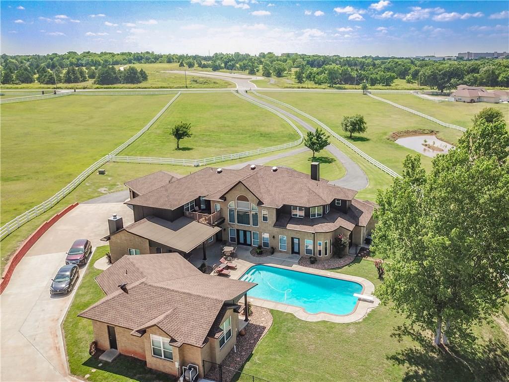 Gated 10 acre Luxury Estate just 5 minutes from OU This home has the best of both worlds.  In-town location with beautiful views of rolling pastures and regular visits of wildlife to the pond.  Main house has a beautiful master suite downstairs with his and hers separate toilet rooms and walk-in closets, double headed open shower, a jetted tub, and a bidet.  The 4 upstairs bedrooms each have their own bathroom.  This home has so many features, built in stereo system, hardwood floors, laundry chute, balcony in front overlooks the pond, upstairs back balcony overlooks the pool and back meadows.  Oversized (992sf) 3 car garage, custom pool, 96 x 42 Cleary building with equipment shop, air cond/heated workshop & a 4 stall horse barn w/ tack rm and wash stall. 695sf Guest/Pool/Party House is completely handicapped  accessible with kitchen, full bath, and huge walk-in closet. Property is completely fenced with white PVC 3 board fencing. 35 minutes to OKC.  Right across the street from John Saxon Park with fitness stations, 3k jogging & biking trails.  Come home to the country while still in town.  This is a bank owned/REO property.  Recent appraisal at $1,025,000. Photos are from 2018.