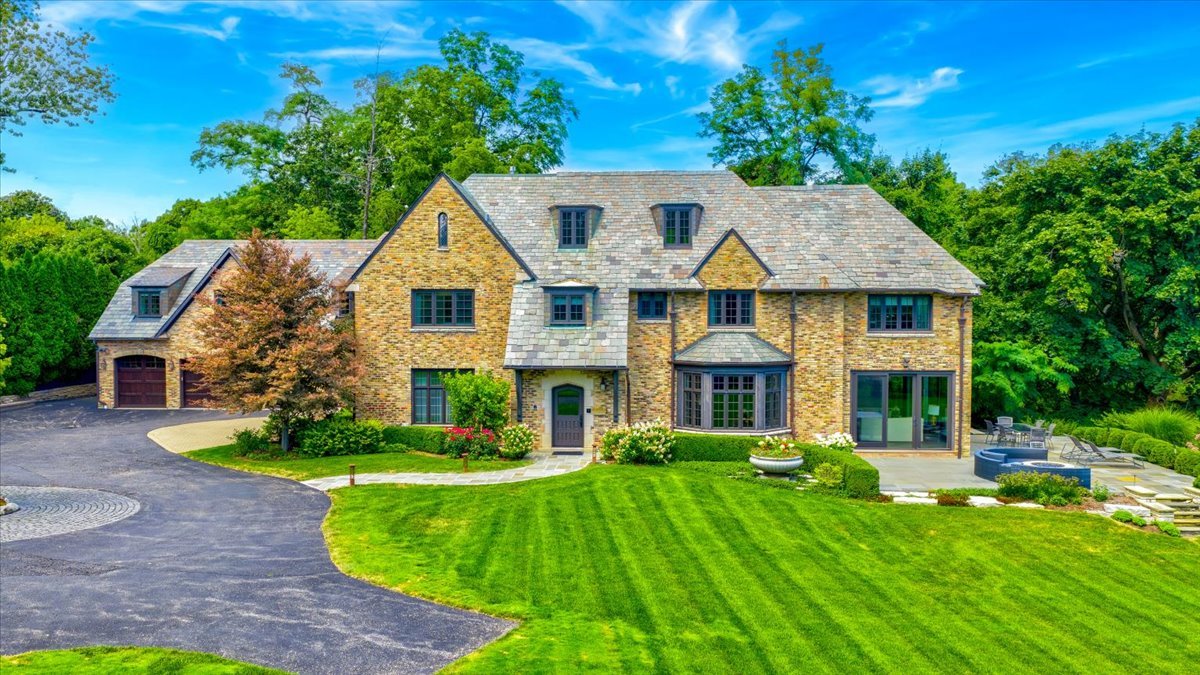 Located in the coveted Belle Avenue Historic District, this extraordinary estate sits on 2.3 acres of manicured grounds with sweeping lake views. Fully renovated and expanded, the residence blends timeless elegance with modern luxury for a truly one-of-a-kind offering. This five-bedroom, eight full and one half bath home showcases craftsmanship of the highest caliber, including a brick exterior, slate tile roof, extensive millwork, crown moldings, built-ins, hardwood floors, expansive windows, soaring ceilings and graciously scaled rooms. No detail was spared in the complete gut renovation and thoughtful addition that restored and elevated this classic beauty. A welcoming foyer leads to a grand living room, perfect for entertaining, with a limestone fireplace, custom built-ins and a wet bar. The living room opens to a light-filled sunroom with three sets of floor-to-ceiling sliders, seamlessly connecting to multiple outdoor entertaining spaces with endless lake views. A formal dining room with herringbone wood floors, custom wallpaper and a crystal chandelier adjoins to a butler's pantry featuring two wine fridges, custom cabinetry and marble counters. The chef's kitchen is a showstopper, with bespoke inset white wood cabinetry, Quartzite counters, decorative marble backsplash, oversized island with prep sink and seating, professional-grade appliances and a walk-in pantry. A spacious eat-in area has 2 sets of sliders that lead to the bluestone patios. The kitchen opens to a large sunken family room that is a perfect gathering spot for family and friends. Additional highlights of the main level include a sophisticated powder room, mudroom with slate flooring and built-ins, full bath, package receiving room and heated three-car garage. Upstairs, the primary suite is a private sanctuary with a cozy sitting area, custom built-ins, dual walk-in closets and a spa-like marble bath featuring vaulted ceilings, a soaking tub, expansive shower, and breathtaking lake views. Four additional bedrooms each include luxury en-suite baths and walk-in closets with custom built-ins. A second-floor laundry with two washer/dryer sets plus a coffee/bar station on the landing outside the family bedrooms add delightful convenience. The third floor, with its vaulted ceiling and abundant natural light, offers a large bonus room with wet bar, office space, home gym/Pilates studio and full bath. The lower level provides flexible living space with a recreation room, game room, sitting area, guest bath and extensive storage. The outdoor spaces are equally impressive, with bluestone patios, a stone fire pit, built-in bar with seating and pristine landscaping overlooking the ravine and lake. This property combines unmatched craftsmanship, spectacular grounds and iconic lakefront vistas-all within close proximity to the lakefront, schools and town. This is a rare opportunity to own a one-of-a-kind stately residence on a stunning property.