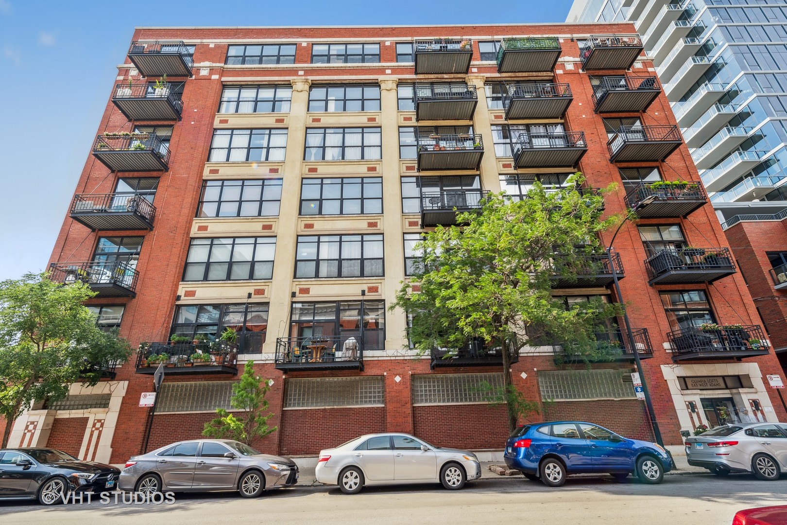 Another rare find at Olympia Lofts, an authentic flat concrete boutique loft building diagonal across the street from Mary Bartelme Park. Residence 310 offers 2 bedrooms completely enclosed with oversized transom windows. Painted in subtle grey and white tones, 5" oak "tongue and groove" hardwood floors with a walnut stain throughout the entire loft, exposed flat 12' concrete ceilings and concrete columns. Open kitchen concept to large living and dining areas. Center island with quartz counters and waterfall edges on both sides with seating for breakfast or informal dining, soft blue cabinetry, stainless steel KitchenAid Appliances, range with fiver burners, 1.25" quartz counters, under mount sink, disposal, black faucet, all white cabinets, uppers with glass panels, soft close drawers, porcelain bricked backsplash, under cabinet lighting. Custom, contemporary lighting fixtures throughout this residence. Living room with sleek fireplace, floating cabinets with quartz counters on each side, open shelving, recessed area for TV and sound bar and central, large format rectangular grey porcelain tiles floor to ceiling. All doors replaced with white panel and black hardware. South facing balcony for barbecue grill and chairs. Beautiful bathroom centralized bathroom features oversized shower and floor hexagon tile, white subway wall tile, rain, handheld and recessed shelf for accoutrements. Two walk in closets. Oversize floor to ceiling storage cage on the same floor as Residence 310 and prime, heated garage parking space (#37) included in list price. Arguably, best neighborhood in Chicago. Skinner Park, Halsted Street for Mariano's and Whole Foods, Restaurant Row on Randolph Street, Madison Ave., Fulton Market, easy access to EL, Metra, train, expressways. Highest concentration of fine dining in one place in the city of Chicago, three City of Chicago Parks and everything in between.