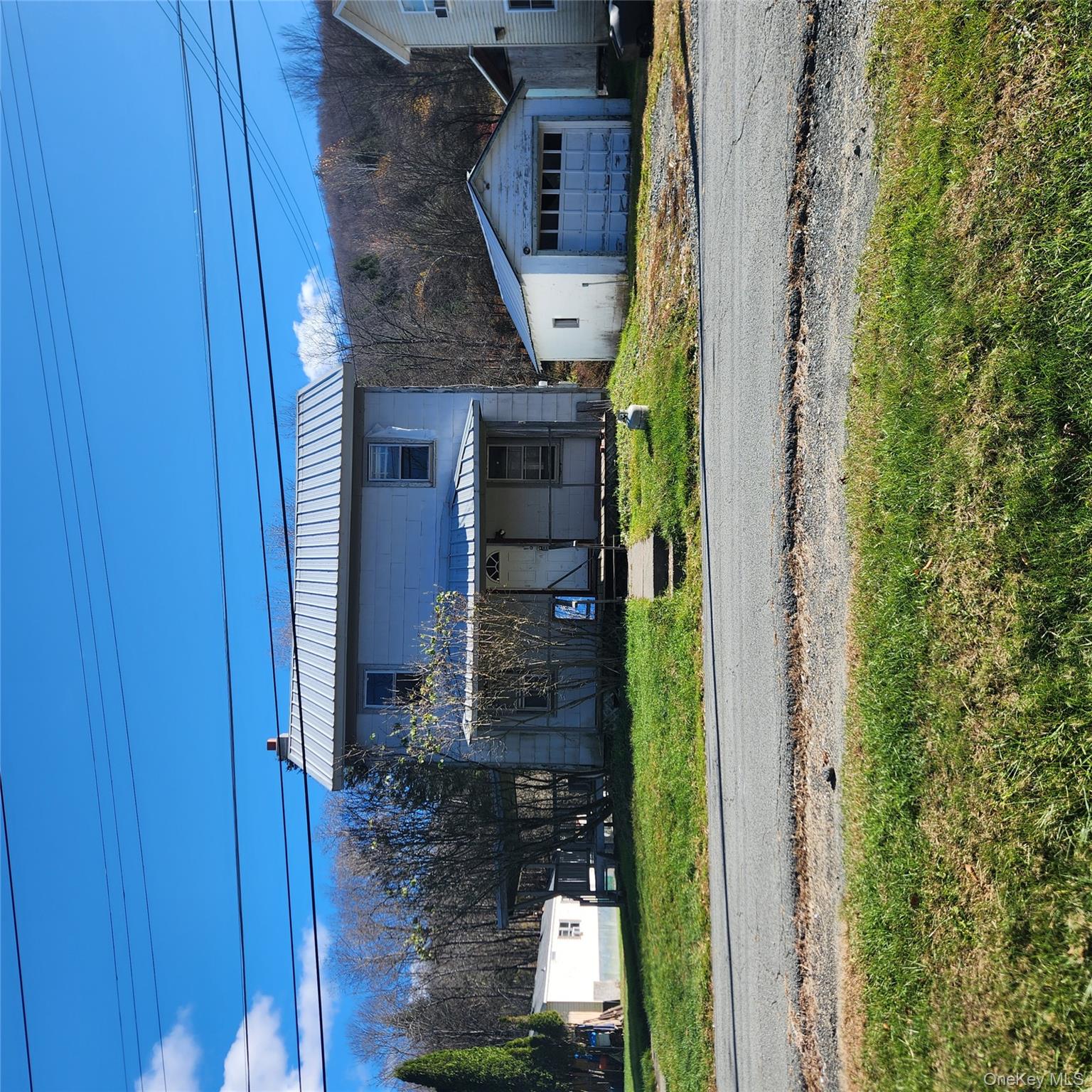 View of front of home with an outdoor structure, a metal roof, a garage, a porch, and a front lawn