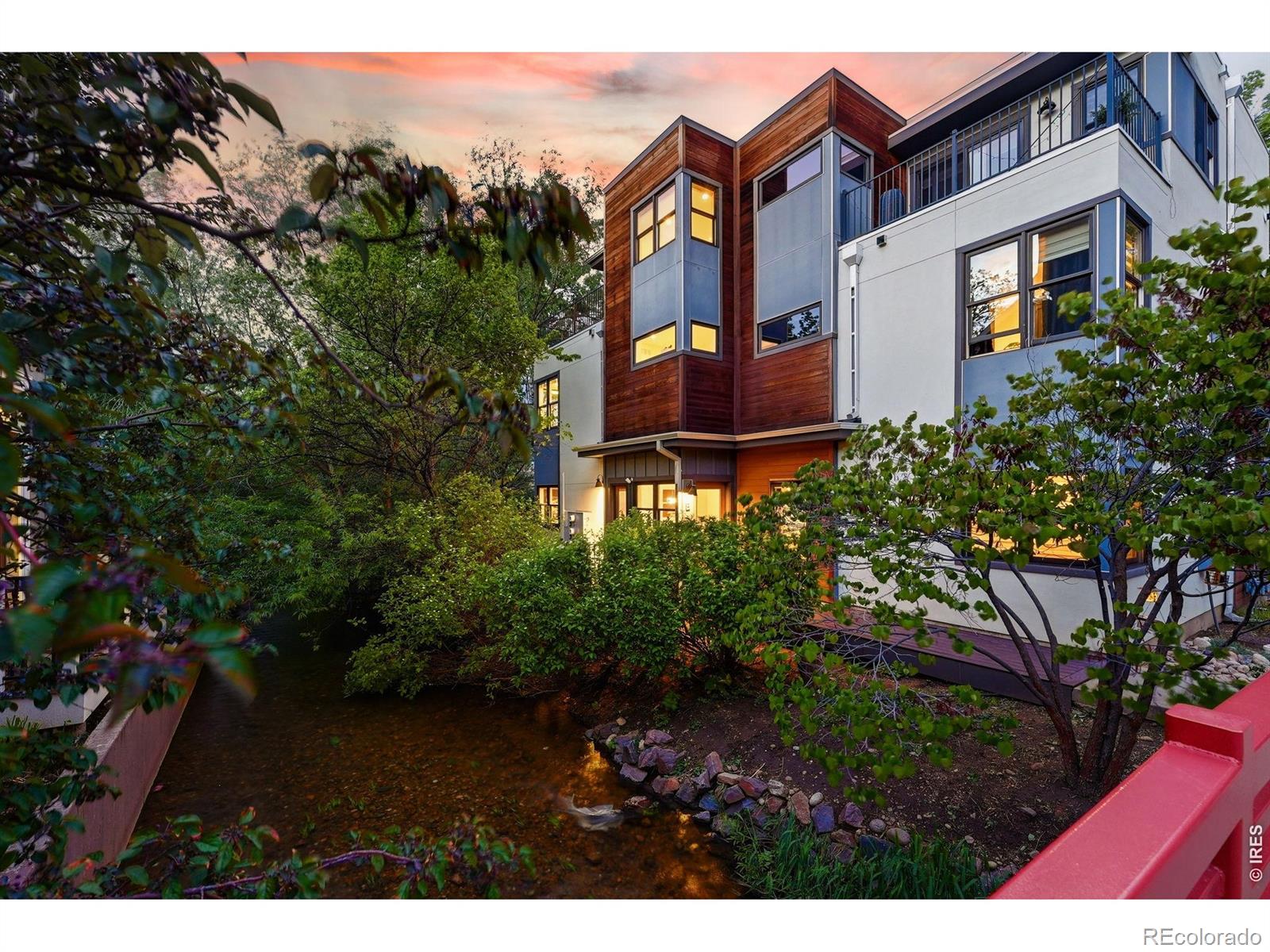 Wake to the sound of rushing water and step onto your deck to take in sweeping Flatiron and Foothill views - this is downtown Boulder living at its most serene.Nestled in a private, quiet community bordered by Boulder White Rock Ditch, the property offers rare seclusion without sacrificing convenience. Lush mature trees wrap the lot, creating a natural sanctuary just minutes from Pearl Street, Boxcar Coffee, and some of Boulder's best dining and nightlife.Inside, an open main-level floor plan flows with beautiful hardwood floors and elevated finishes throughout. The living and dining areas connect seamlessly for effortless entertaining, while the kitchen anchors the space with a center island with seating, stainless appliances, rich wood cabinetry, and Carrara marble countertops.The top-floor primary suite is a true retreat with Flatiron views, an oversized balcony, custom walk-in closet, and a spa-inspired bath with Carrara marble. Two additional well-sized bedrooms share a stylish dual-entry bath.Outside, an expansive deck perched among the treetops sets the scene for summer gatherings or quiet evenings with a glass of wine. Neighborhood trailheads are moments away for those who want to explore the foothills as easily as the coffee shops. An attached 1-car garage with built-in storage and an in-unit washer and dryer round out this exceptional offering.