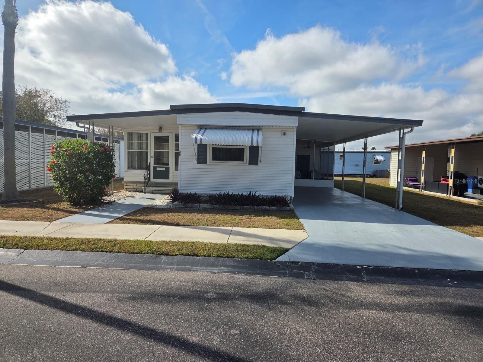 This unique 3-bedroom 2-bath mobile home is located in this quiet community of only 75 homes. This home has many upgrades, including an added 10x18 enclosed Florida Room, & Screened in porch. There is plenty of storage with a 8x16 Workshop/Double Shed. The Washer/Dryer is conveniently located inside the home, Laminate Floors throughout, many new windows, and a newer Central Air/Heat Unit '21. Insulated Double Roof & Vinyl Siding and Attached Covered Parking for 2 Cars! This community allows one small pet under 20 pounds, has a heated pool, shuffleboard court, and an active clubhouse with lots of activities.  Price is including the share, cash only! Low fee of $230 a month, including water, sewer, trash, lawn care.
