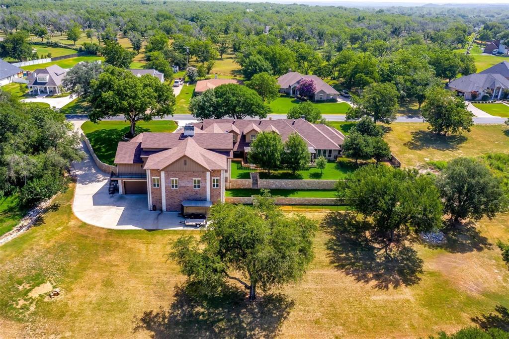 Extraordinary & luxurious estate in Pecan Plantation, beautifully situated along the historic Brazos River in Granbury, TX. This remarkable property is a harmonious blend of luxury, comfort & functionality, masterfully designed & remodeled by award-winning builder Chris Thomas who also added living square footage, garages & site improvements to the property beginning in 2018. Nestled on 3+ private acres with over 300 feet of deep, river frontage, this stunner offers more than 9,000 square feet of living space designed for both elegant entertaining & everyday living. Inside, you’ll find a spacious floor plan featuring 5 bedrooms, 4.5 bathrooms, multiple living & flex spaces, including a spectacular, 3,000-square-foot entertainment room complete with a majestic, one-of-a-kind, custom floor-to-ceiling, stone with pine mantels four-way propane fireplace & full pub-style bar. The home is filled with premium amenities including Renewal by Andersen windows, custom cabinetry, granite countertops, double ovens, 6 burner propane cooktop, wine fridge, Butler’s pantry, mud room, craft room, plantation shutters, storage, 2 home offices, cathedral ceiling, beamed ceiling, retainer wall, fishing pier, 3 hot water heaters-1 being tankless, 3 dishwashers, foam insulation & garage space for 7 vehicles or vehicle + RV storage. Located within the security-gated community of Pecan Plantation, residents enjoy one of the most unparalleled lifestyle experiences Texas has to offer. With easy access to Lake Granbury, this community features 2+ golf courses, 2 airstrips, 2 pools, marina boat launch, horse stables, campground, walking trails, pickleball, basketball, tennis courts, restaurant & more. Country club & community center with numerous social activities. Minutes from community grocery store, gas station, bank, car wash, liquor store, restaurants, etc. Resort living @ its finest! Best kept secret in TX! This is more than a home-it's a destination! Bonus: NO CITY TAXES!