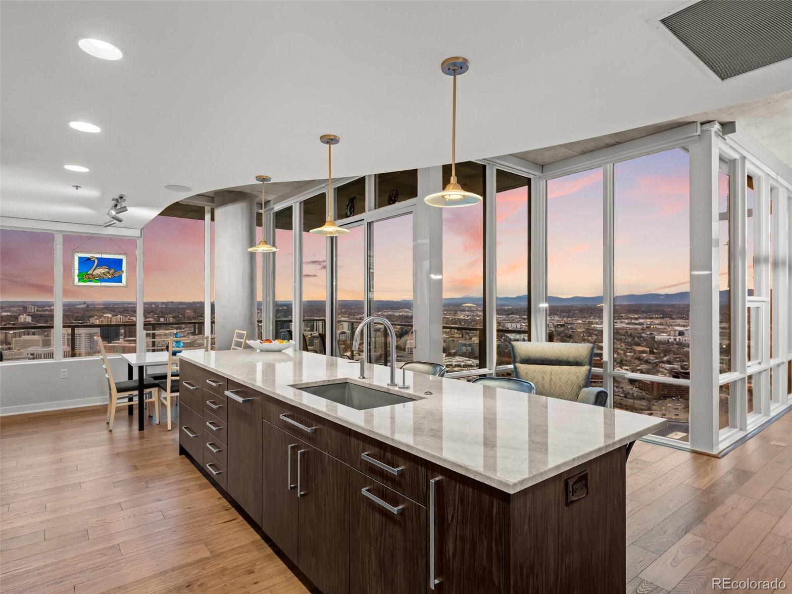 Experience the pinnacle of urban luxury in SPIRE Residence #3916, a masterfully renovated corner retreat perched high on the 39th floor of Downtown Denver’s most iconic condominium community. Spanning 1,671 square feet, this sophisticated residence features new mahogany hardwood floors and expansive floor-to-ceiling windows that frame breathtaking panoramic views of the Rocky Mountains, Pike’s Peak, Mile High Stadium, and the shimmering city skyline. The open living space flows seamlessly onto dramatic wraparound balconies, offering an unparalleled outdoor vantage point. At the heart of the home is a sleek, timeless kitchen equipped with a massive quartzite island, custom cabinetry, and premium Bosch and Thermador appliances. The primary suite serves as a private sanctuary, boasting rift-sawn white oak cabinetry and a spa-like en-suite bathroom finished with slab granite, Carrera marble trim, and a custom walk-in closet. The second bedroom also offers jaw-dropping views and its own en-suite bathroom adorned with Carrera marble. This exceptional property includes two parking spaces and a storage cage in the attached garage, along with a rare, private indoor storage closet located on the 27th floor. Every detail of this home has been curated with the finest materials to provide a lifestyle of elegance and convenience in the center of the city. Own this home and gain access to the exclusive 42nd-floor SkyClub Lounge. Certain furniture is available for an additional fee. SPIRE is FHA-approved! Life at the LEED-certified SPIRE offers a resort-caliber experience, featuring a health club, year-round pool, hot tub, and a multimedia theater. Residents enjoy the convenience of a 24-hour courtesy desk, guest suites, grilling area, and pet-friendly amenities including a dedicated dog park. You are invited to experience the vibrant energy of the city from the most coveted heights in Downtown Denver. Come home to Downtown Denver's SPIRE--life is better here!