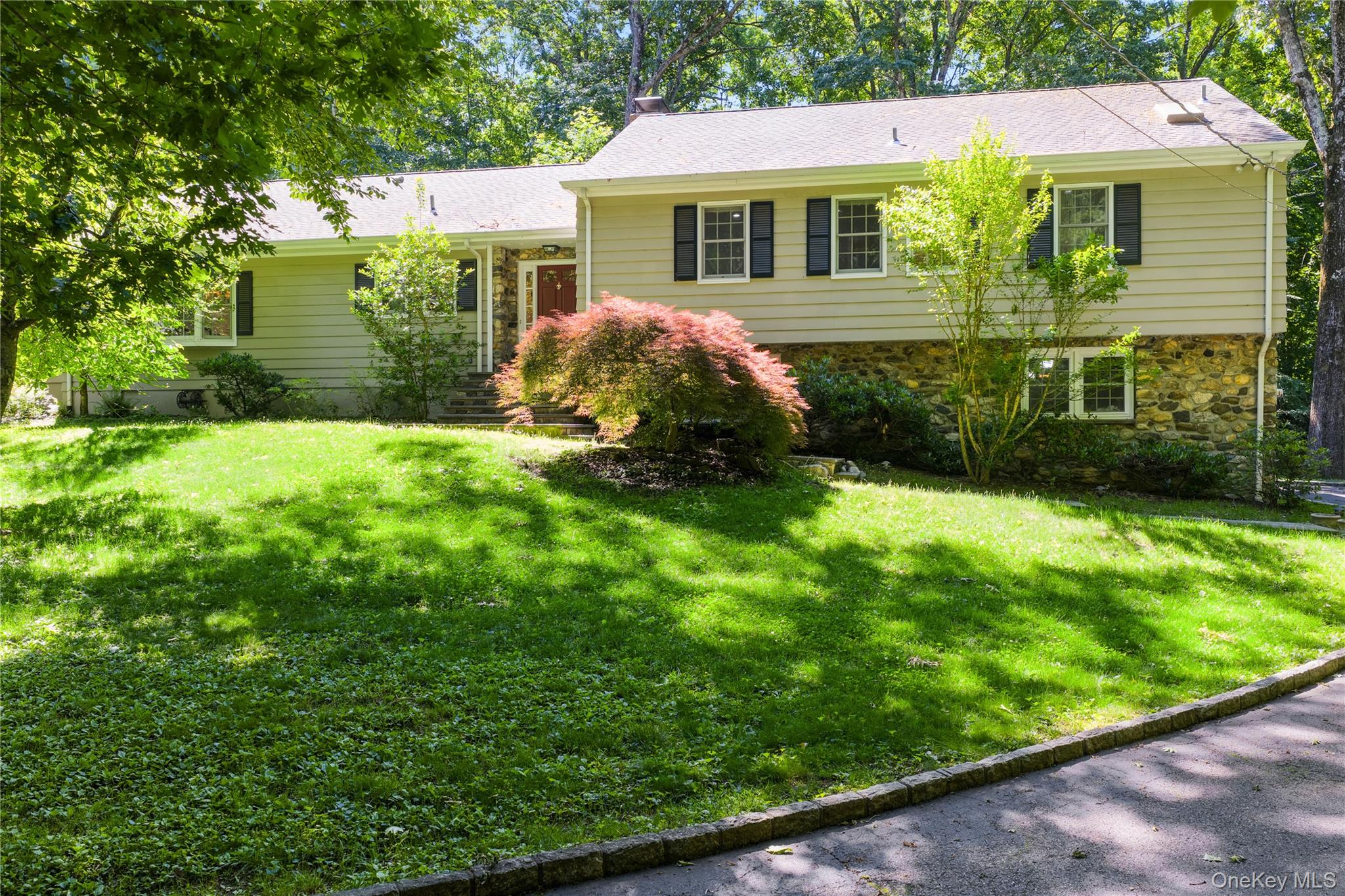Beautifully updated split ranch set on 1.02 park-like acres in a sought-after Chappaqua location near school, train and walkable to village center train and shops. The heart of this home is a spectacular high-end renovated eat-in kitchen featuring white cabinetry, Wolf, Miele, and Sub-Zero appliances, honed marble and granite counters, a center island with pendant lighting, a peninsula with seating, a walk-in pantry, bay window and a door to the patio-all flowing seamlessly into the living room with stacked stone fireplace, family room, and large dining area with bay window and crown molding. Wide-board pegged oak hardwood floors, crown molding and an abundance of natural light enhance the warm, inviting ambiance throughout.The living room showcases a dramatic floor-to-ceiling stacked stone raised hearth fireplace and custom built-ins. The light-filled family room impresses with soaring ceilings, a skylight, windows on three exposures, and French doors opening to a slate patio- perfect for indoor-outdoor living. A windowed main-level laundry room with built-ins and a renovated powder room add everyday convenience.Upstairs, are four bedrooms-three generous bedrooms with wide-board pegged oak floors and double closets share a newly renovated hall bath with double-sink vanity and full tub. A privacy door leads to the primary suite with king-size bedroom, oversized windowed walk-in closet, and an updated en-suite spa style bath with skylight, jetted tub, large storage vanity and frameless glass shower.The expansive lower level offers exceptional flexibility and has a playroom with sliding glass doors to a lower patio, home office, powder room, large mudroom, and an oversized two-car garage with storage alcove. The fenced backyard with multi-level patios and flat lawn presents a potential pool site. Additional features include new windows, professional landscaping, wired-for-generator, EV charger, closet organizers, 10-year new roof, 4 zone HVAC, and low taxes. Truly move-in condition, a gem, won’t last.