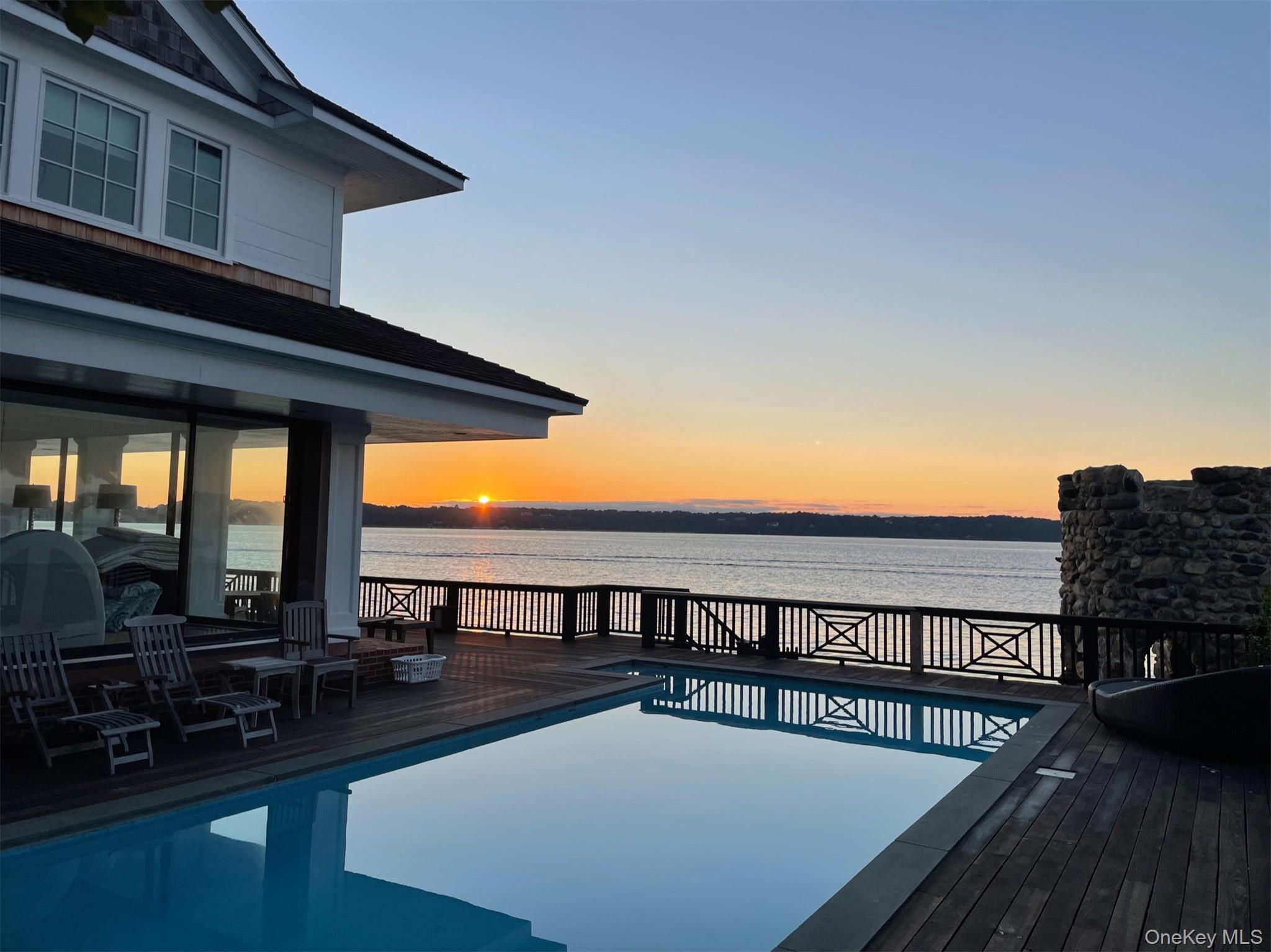 Summer Oasis on Centre Island, where Oyster Bay Harbor Meets the Sound. Experience a rare opportunity to spend your summer at this premier waterfront estate. Perched on a private point, this home is completely embraced by the water, offering a front-row seat to the best of Gold Coast living. The Great Rooms floor-to-ceiling water views greet you the moment you step inside, flowing seamlessly onto a massive wrap-around deck. Relax by the pool that hovers over the harbor, or enjoy an outdoor shower after a day at the beach. Watch the boats navigate the harbor by day and toast to world-class sunsets over the Long Island Sound by night. Five spacious bedrooms—all located on the second floor—feature private views of the water. The home features a fully equipped Gourmet Kitchen for summer entertaining, Great Room, cozy Den with TV, and expansive decking. The lower level has a bonus room and full bath. Exclusive access to two private sandy beaches. A summer dream come true and wonderful Hamptons Alternative.