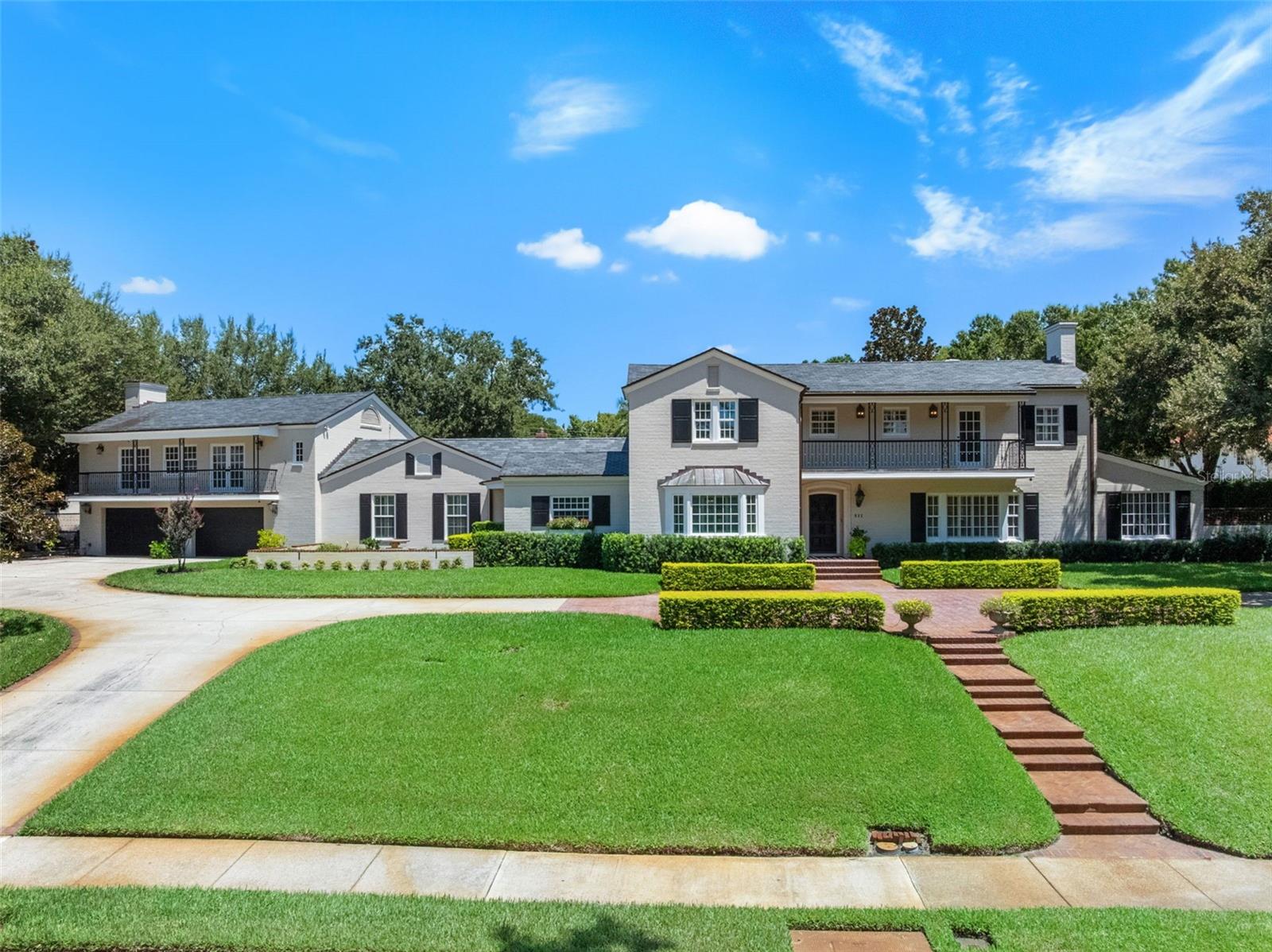 One of the largest estate homes in College Park, this 5 bed, 5.5 bath residence sits on over 3/4 of an acre with 200 feet of lake frontage in the Lake Adair–Lake Concord Historic District. Built in 1946 and massively expanded by McCree, a respected Orlando design-build firm. The home was thoughtfully renovated to blend high-end function with refined design. The chef’s kitchen features Wolf, Miele, and Sub-Zero appliances, soapstone counters, brass fixtures, dual pantries, and an adjacent wet bar with wine fridge and glass-door built-ins. The formal dining room, living room, and sunroom all overlook Lake Adair. The first-floor primary suite includes two walk-in closets, a soaking tub, and marble shower. Upstairs are four bedrooms and three baths, including a flexible second primary with a sitting room, mini fridge, microwave, and private lakeview balcony. Above the oversized double pass through garage is a full guest studio with kitchen, steam shower, and another lake-facing balcony. Additional features include two gas fireplaces, solar panels (typically covering the full electric bill), electric car hookup, updated systems, a lifetime slate roof, and a walled backyard. Located in walkable, lake-filled College Park—known for its small-town feel, Edgewater Drive shops and dining, and close proximity to downtown, Dr. Phillips Center, Kia Center, Orlando City Soccer, Winter Park, hospitals, the airport, and theme parks.