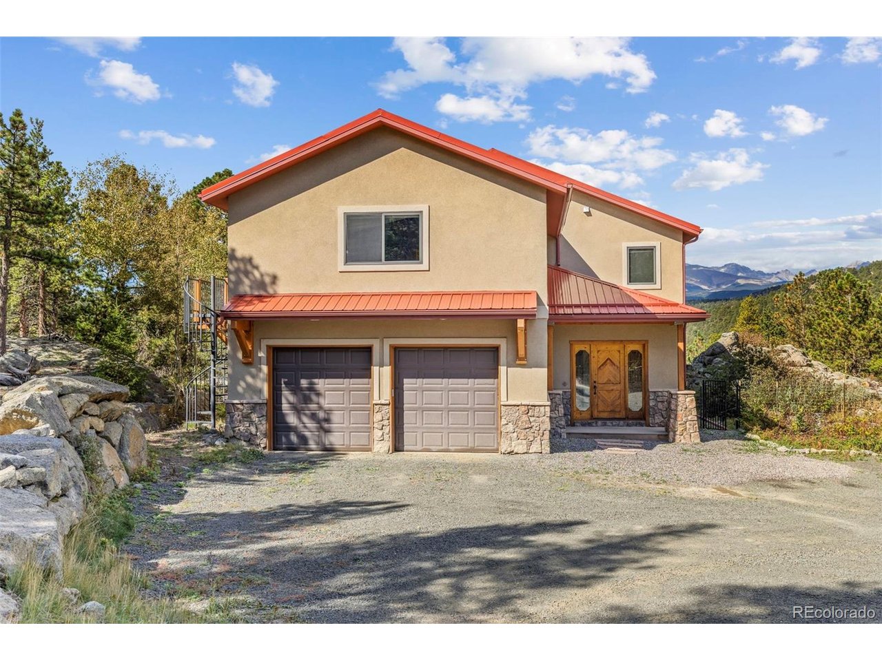Located at the end of the road, this custom stucco home, built in 2007, occupies 7 private acres in a coveted neighborhood just minutes from Nederland, with 3 sides adjoining National Forest. Framed by dramatic rock outcroppings and sweeping snowcapped Indian Peaks views, this exceptional property offers refined craftsmanship, seclusion and direct access to nature. A private drive leads to a level parking area and oversized 2-car garage. Inside, the tiled foyer opens to an inviting open-concept main level designed for living and entertaining. The well-appointed kitchen features granite counters, a 4-person bar, stainless appliances and an oversized pantry, while the adjacent dining and living areas showcase newly refinished hickory floors, tall ceilings and a wall of windows capturing the mountain panorama. Step outside to a spacious composite deck and flagstone patio that leads to a hot tub nestled against tumbled boulders. A dedicated office with Murphy bed offers flexibility as a 4th bedroom, while a half bath completes the main level. Upstairs, 3 generous bedrooms accompany a massive rec room/flex space with balcony, views and a metal spiral staircase to the grounds. The primary suite is oriented toward the views and features an ensuite with soaking tub, separate shower and private balcony with spiral stairs to the deck. An owned solar system helps offset energy costs. A fenced yard provides space for pets or play, while rock outcroppings and a private trail system lead toward National Forest and miles of hiking from your doorstep. The basement offers potential for future finished space, with a finished laundry room already in place. A metal roof and new tankless water heater add to the home's enduring appeal. Just 10 minutes to Nederland and an easy, scenic commute to Boulder via the summer access road, this is a special mountain property with the quality, setting and timeless appeal to become a legacy home for generations.
