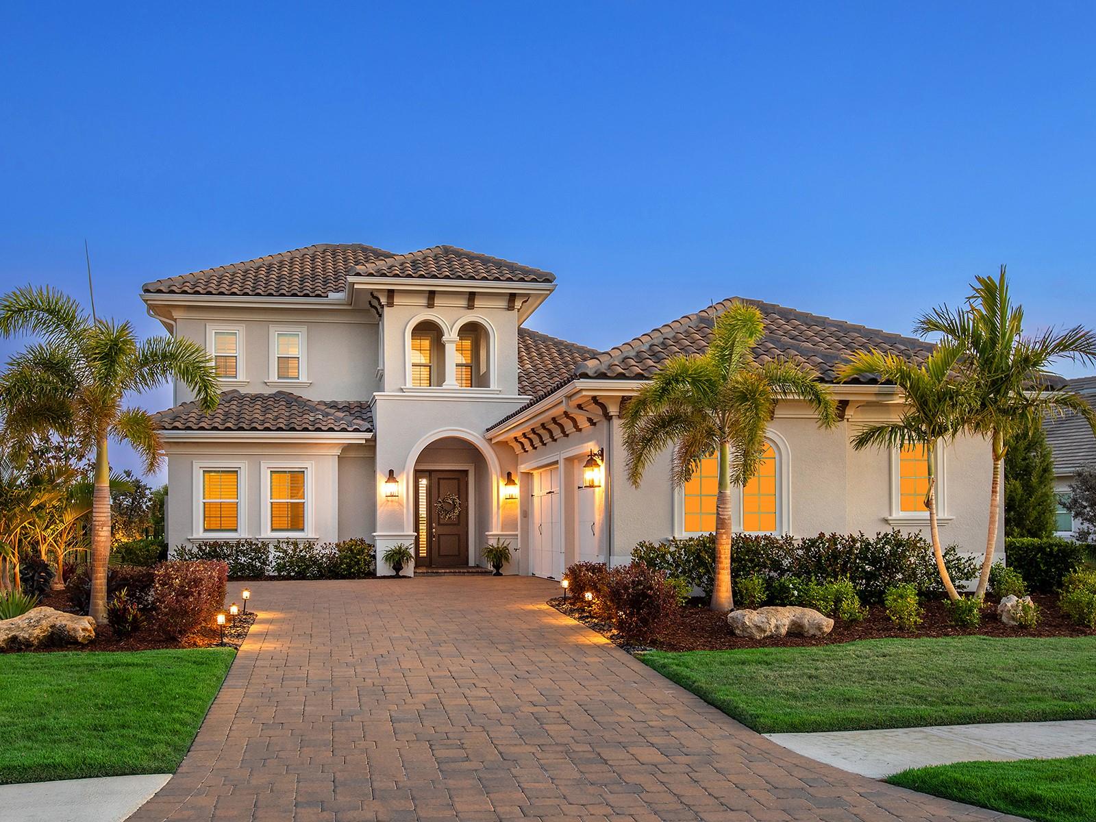 This is an exceptional residence tucked within the gates of Lakewood Ranch’s exclusive community, The Lake Club. With its elegant Eaton Grand III floor plan, this 2021-built estate offers effortless luxury. The home’s stately curb appeal sets the tone from the moment you arrive, with a side-load three-car garage, oversized paver driveway and manicured landscaping. Step through the front door into a soaring foyer adorned with accent trim, crown molding and a designer chandelier. Throughout the home, rich engineered hardwood flooring, plantation shutters, and sophisticated finishes speak to the care and detail poured into every room. The great room is an expansive space framed by a wallpaper accent wall and a striking linear fireplace with herringbone shiplap and a wood mantel. Pocketing sliders disappear to connect indoor-outdoor living. The kitchen boasts stainless steel KitchenAid appliances, including a five-burner gas cooktop with a statement hood and built-in oven and microwave/convection, granite countertops, stone backsplash and abundant cabinetry with under-cabinet lighting. A generous pantry cabinet, a lazy Susan corner cabinet, and an oversized island create ease for daily routines and entertaining. Just off the kitchen, the dining area is flooded with natural light from two large windows and elevated by a designer chandelier. Secluded in its own wing, the primary suite is a private retreat featuring an alcove entry, shiplap accent walls, a sitting area and two custom walk-in closets with thoughtful built-ins. The en-suite bath is complete with dual vanities, a soaking tub, a walk-in shower and a private water closet. Three additional bedrooms provide comfort and flexibility. One guest suite includes a private bath, while two more share a full bath in a cleverly designed pocketed guest wing. A quiet office, accessible through French doors, offers the perfect space for a home office or library. Upstairs, the loft offers versatile bonus space while an adjacent fitness room, or potential fourth bedroom, features three large windows and a spacious closet. A full bath with quartz-topped vanity and tub/shower completes the upper level. Step out to the lanai and enjoy a covered seating area centered around a custom media wall. The fully equipped summer kitchen includes a built-in Blaze grill, sink, mini refrigerator and granite countertops. The saltwater pool and spa await with blue tile accents, LED lighting, waterfall bowls with fire features and a sun shelf. A dedicated pool bath with quartz vanity and tile floors adds ease, and the included sauna invites relaxation. A brand new pool and lanai screen was installed July 2025. The fenced yard, bordered by mature landscaping, creates peace of mind for pets or children. Additional features include a well-appointed laundry room with granite counters and ample cabinetry, a large storage space under the stairs and a spacious three-car garage. In The Lake Club, residents enjoy access to a wealth of amenities, including two resort-style heated pools, a recently renovated clubhouse with fine dining and bar area, a fitness center, spa, tennis courts, pickleball, a playground, dog park, and services of a full-time concierge and activities director. Additionally, residents are near The Mall at UTC, LWR Main Street, Waterside Place and dining options. Experience luxury living in this home, where every detail has been carefully considered to provide the ultimate Lakewood Ranch lifestyle.