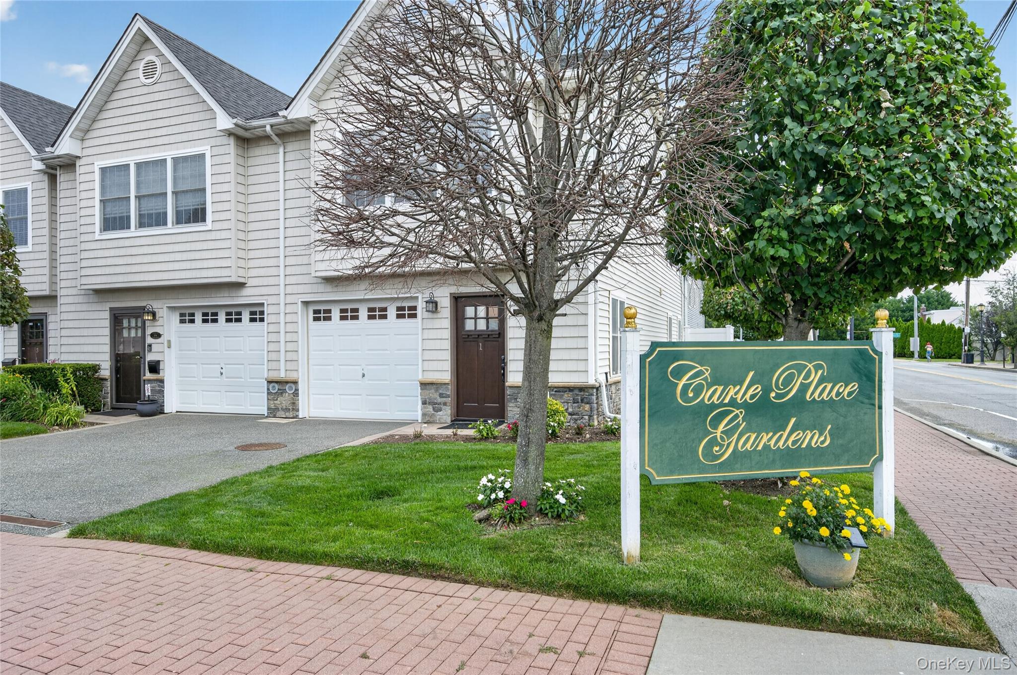Welcome to 1 Koch Place, (62 + age) community development named Carle Place Gardens-, a beautifully updated two-story corner-unit condominium in the highly sought-after Carle Place Gardens, located within the Carle Place School District. This bright and inviting home offers the perfect blend of style, comfort, and functionality.  Step inside through the welcoming entryway and discover an open, airy floor plan enhanced by elegant crown molding, and abundant natural light. The stunning updated eat-in kitchen features timeless shaker cabinetry, stainless steel appliances, and an island with counter seating—perfect for casual dining or entertaining. The kitchen flows seamlessly into the formal dining room and spacious living room, creating an ideal space for everyday living and hosting guests.  French doors lead to the gorgeous primary suite, complete with a walk-in closet and a beautifully appointed en-suite bath. The renovated bathrooms showcase exceptional custom tile work and modern finishes throughout. A large, sun-filled den with sliding glass doors opens to a private paver patio, offering the perfect outdoor retreat for relaxing or entertaining.  Additional highlights include central air conditioning, an in-unit laundry area with washer and dryer, and the added privacy of a desirable corner location. Ideally situated near shopping, restaurants, parks, major roadways, and the LIRR, this move-in-ready home offers low-maintenance living in one of Carle Place’s most desirable communities.
