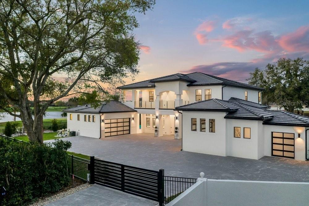 Welcome to 11 Bay Hill, perfectly positioned on the 11th hole with 253 feet of breathtaking golf and water frontage overlooking the world-famous PGA course. This newer custom contemporary estate is an architectural showpiece, privately tucked away on a cul-de-sac with a long private drive and gated entry. Nearly two years in the making, the home was thoughtfully designed to capture sweeping panoramic views while offering exceptional comfort and privacy. From the moment you enter, the large porcelain tiles makes a striking statement, meticulously installed to complement the home’s custom design. Soaring 22-foot ceilings and 9-foot sliding glass doors fill the interior with natural light. At the heart of the home, a double-island chef’s kitchen opens seamlessly to the family room and features Sub-Zero and Wolf appliances, along with an impressive 534-bottle wine cellar. Throughout, flawless Level 5 finishes highlight the extraordinary craftsmanship. The main-level primary suite is a true retreat, complete with a private sitting area and a spa-inspired bath. Outdoors, an expansive living area sets the stage for unforgettable sunsets, centered around a glass-mosaic, infinity-edge heated pool with a 360-degree spa and dramatic fire bowls. 11 Bay Hill is a rare, one-of-a-kind golf-front estate and a once-in-a-lifetime opportunity to own a property that will be admired for years to come offering an exceptional lifestyle from the moment you pass through the gates. Be sure to click on virtual tour links.