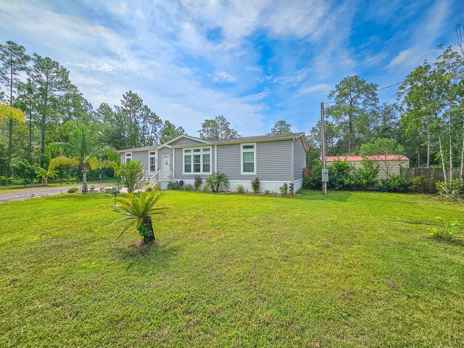 Former Model Home ~ This 3 bedroom, 2 bath manufactured home sits on just under 1 acre in Daytona North. This Beautiful Home was previously showcased as a dealer model- offering a great opportunity to own a home that’s loaded with upgrades. It’s been well maintained and is move-in ready with just under 1,500 square feet of living space. Home features crown molding throughout, transom windows that let in extra light, and a large center island in the kitchen perfect for gathering and entertaining. With modern finishes, stylish cabinetry, and quality flooring that gives it a clean, upgraded feel. Out back, enjoy a large, covered paver rear patio and plenty of space to relax, garden, or add your own personal touch. With so much land and a fresh interior, this home offers the best of both comfort and room to grow. Everything was designed to show off the home at its best- If you're looking for a nice home that’s ready to go, this one’s worth a look