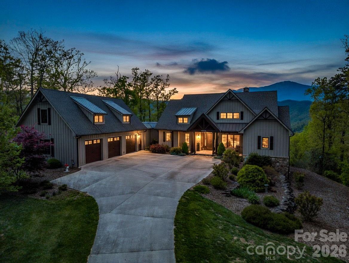 Offered fully furnished. Perched against the breathtaking silhouette of the Blue Ridge Mountains, this exceptional 4.11-acre estate offers a rare blend of refined luxury and natural beauty. Designed for those who value privacy and prestige, the home serves as a peaceful retreat where thoughtful architecture complements its rugged surroundings. A striking exterior of natural stone and classic board-and-batten siding is framed by professional landscaping that blends seamlessly into the surrounding forest, creating an immediate sense of arrival. Inside, the home embraces its setting with organic textures and expansive windows that frame stunning seasonal views. The great room is the centerpiece, featuring soaring vaulted tongue-and-groove ceilings supported by heavy timber beams and a dramatic floor-to-ceiling stacked-stone fireplace. This inviting space flows effortlessly into a well-appointed kitchen, where rustic character meets modern convenience. Custom dark-wood cabinetry, premium stainless steel appliances, and a large granite island with an induction cooktop create a setting for everyday living and entertaining. A full covered and screened deck extends the living space outdoors. The primary suite offers a private retreat, complete with its vaulted timber ceiling and direct access to the screened deck. The en-suite bath is designed for relaxation, featuring a freestanding soaking tub, a glass-enclosed shower with detailed tilework and custom wood accents that reflect the surrounding landscape. The main level also includes an additional bedroom and full bath, a private office, a walk-in pantry and a separate laundry room. The lower level, accessible by elevator and stairs, provides an ideal space for recreation and guests. Polished concrete floors, a second stone fireplace and a distinctive Coca-Cola-themed bar give the space a unique character, while the guest en-suite bedroom offer comfort and privacy. There is an additional bonus room with an en suite and ample storage is available throughout. Go out onto the lower patio to enjoy the gas fire pit or hot tub while taking in the mountain views. Outside, the property continues to impress with expansive decking, a three-car attached garage and over 600 unfinished square feet above the garage ready for customization, ideal for a guest suite, studio or additional living space. This is more than a home, it’s a mountain retreat designed for comfort, style and lasting connection to nature.