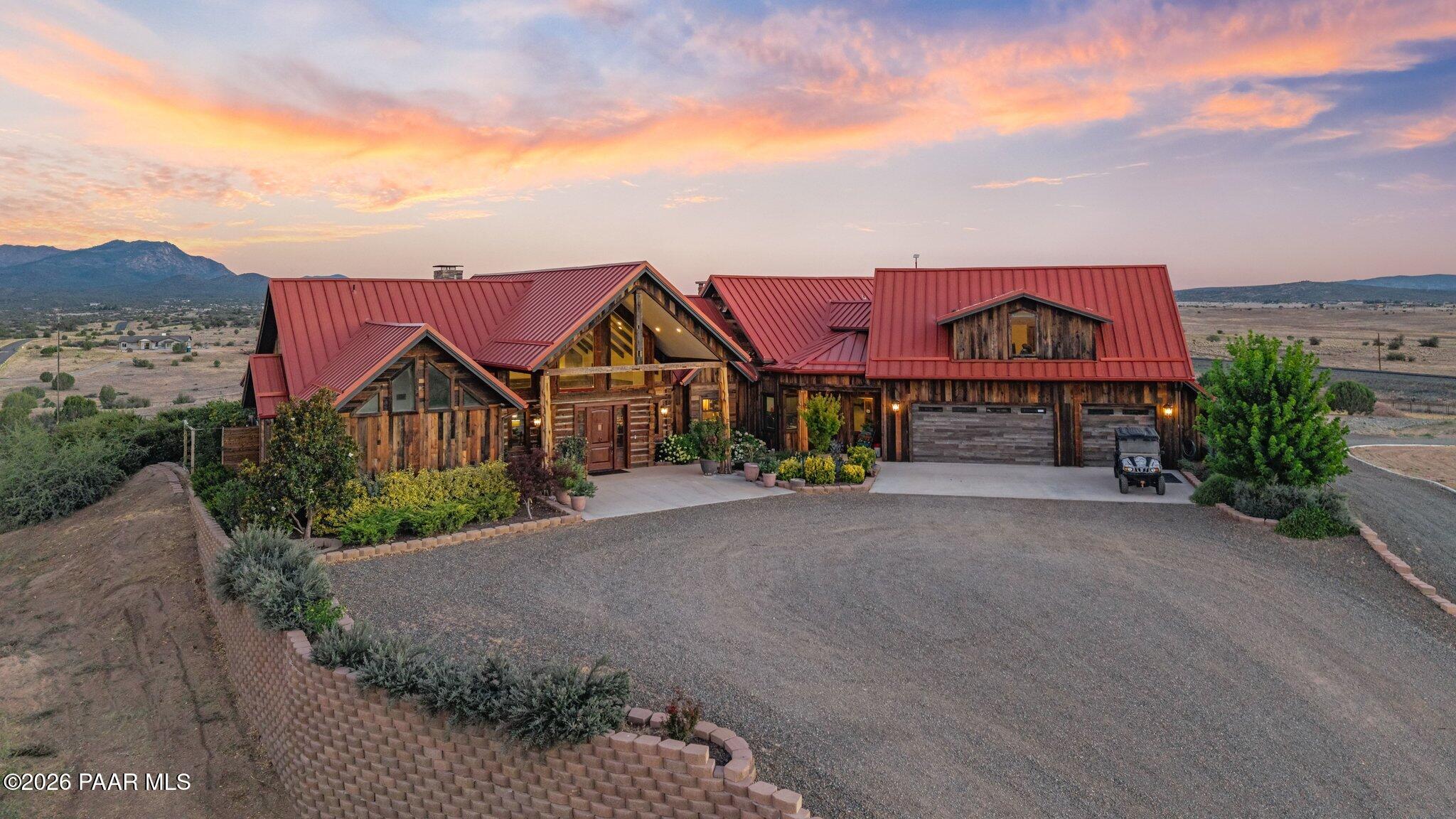 Luxury Vineyard Log Estate on 37 acres. Some homes are built. This one was earned. In 2021, owner's vision became a reality that few will ever replicate, an authentic, reclaimed log home constructed from a dismantled century-old Indiana barn. Every log was carefully removed, transported across the country, & reassembled here in Prescott. Each beam was hand-hewn from solid trees, several full trees went into the making of this home, resulting in a structure w/ genuine soul, history, & craftsmanship that simply cannot be recreated today.  Step inside & the story continues. Stunning magnesium tile flooring w/ warm wood accents, imported from Mexico, flows underfoot, while a striking Cantera stone fireplace anchors the living space as a natural work of art. Rich white oak woodwork carries throughout the home's 4,482 square feet, a two-story layout thoughtfully designed with main-level living at its heart. 4 bedrooms plus office, 6 bathrooms. The grand chef's kitchen invites gathering & celebration, while the spa-inspired primary suite, complete w/ one-of-a-kind soaking tub created from a solid piece of granite that was hand carved & outdoor shower offers a private retreat that rivals any five-star resort. The story doesn't end at the front door, this estate is a working vineyard, where the owners hand-grow & produce their own wine, pressed on an authentic Italian press shipped directly from Italy. Inside, a hidden wine room tucked beneath a graceful staircase offers the perfect place to store & savor each vintage.  Beyond the main residence, three additional structures provide an impressive 14 parking spaces w/ ample room for toys, equipment, RVs & more.This is more than a luxury property. It's a decade-long labor of love, a working vineyard, & a one-of-a-kind reclaimed log estate, all set against the natural beauty of Williamson Valley. Homes like this simply aren't built anymore, call today for your personal tour.  This is a definite must see in person to fully appreciate!
