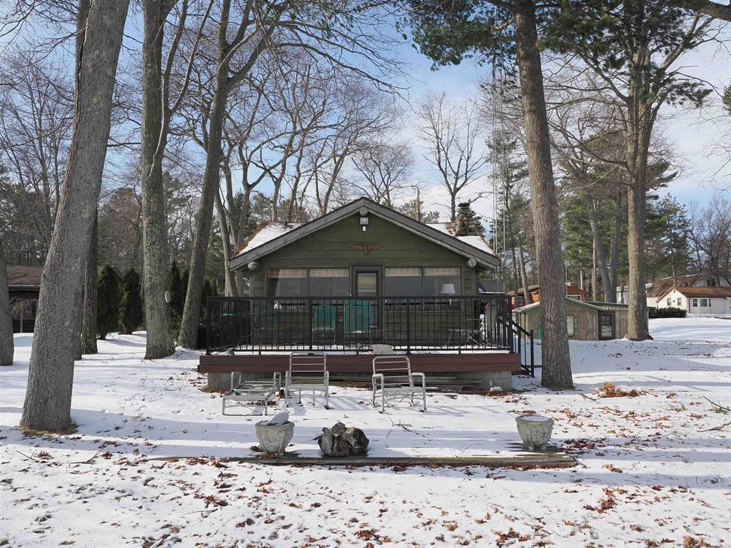 This classic Lake Huron log cottage is warm, cozy, and inviting-just like the traditional cottages we remember from our youth. The property includes a double lot with 100 feet of south-by-southeast frontage, offering beautiful sunrises over the big lake. A vacant lot across the road is also included, providing space for extra parking or the potential to build a guest house or garage.  The cabin retains its original charm, centered around a beautiful stone fireplace in the living room. Despite its rustic feel, it features full plumbing and central heat, allowing for comfortable year-round use. The two lots and the lakeside deck provide ample space for outdoor activities.  The 100 feet of frontage has been reinforced with a riprap seawall, and the sandy, shallow lake bottom beyond it makes for excellent swimming and water sports. If desired, the property could also serve as a great building site for a new home.  There is a guest house on the property, though it is in questionable condition. The cabin is conveniently located just off US-23 for easy access, and the vacant lot extends from US-23 to the cabin-allowing for a potential drive-through layout if desired.
