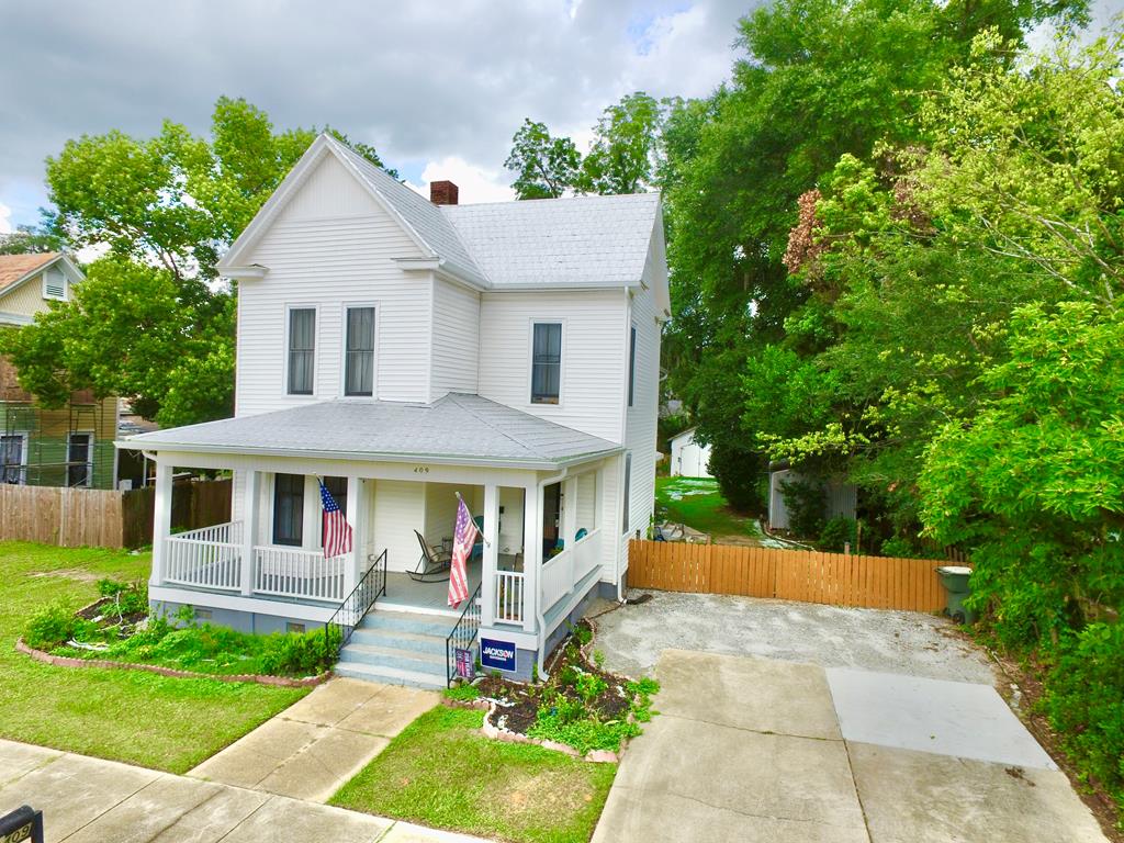 Experience timeless elegance in this beautifully restored early 1900s Neoclassical Revival home, perfectly situated in downtown Bainbridge. Combining historic character—featuring original hardwood floors, soaring ceilings, and four fireplaces—with modern convenience, this residence offers a seamless blend of past and present. Enjoy expansive living spaces, a classic full front porch, and a private, fenced yard with established fruit trees. Recent professional upgrades include all-new electrical, plumbing, and HVAC systems, ensuring absolute comfort. With an oversized garage, a versatile workshop, and thoughtful storage throughout, this home is a rare masterpiece of enduring craftsmanship.