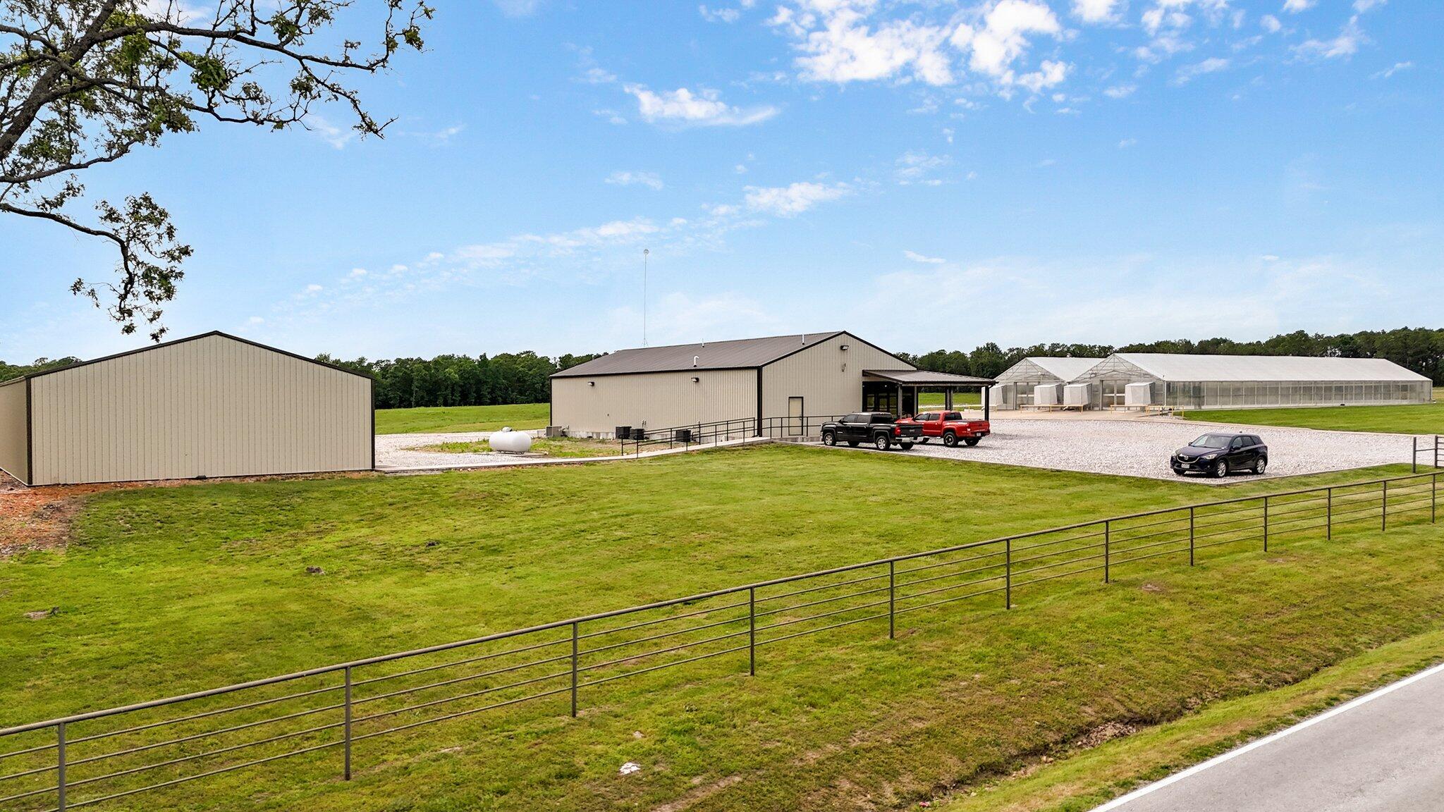 This is an incredible state of the art greenhouse and farm, with multiple opportunities available, and 30 acres to expand. It is located in the heart of the Ozarks, being an hour from Springfield, Northern Arkansas, and 45 minutes to Joplin, all cities with major outlets for agricultural products. Alongside this nearly 8000 sq ft greenhouse are two 40 x 80 outbuildings, and another concrete pad and materials for the construction of another greenhouse. The front building houses a beautifully designed office featuring a stunning glass front with covered wrap around porch, Inside, a brick accent wall adds warmth and character, complemented by a wood ceiling with exposed beams for a sophisticated modern atmosphere. This space is fully equipped with a full kitchen, along with a full bath, perfect for team meetings & client entertaining. If you are looking for a stylish showroom or a functional office area, this building offers versatility to meet your business needs and is also ADA compliant. The near 8000 square foot greenhouse boasts every state-of-the-art amenity available, with a MicroGrow PROCOMII Control panel, computerized monitoring & storing of data. There are 4-250,000 BTU/HR propane heaters. Lighting is Ceramic Metal Halide that can operate on 1 or 2 phase. The ventilation system offers 8 circulation fans and 4 exhaust fans. The alarm system sends both text & email if humidity or temperature fluctuates out of the programmed range.  The MicroGrow WATERMAX system can also be automated & includes a gravity operated fertigation system with 2-250 gal tanks in the office building equipped with Big Blue Filter and UV purification.  A 50% Shade system, also a fire retardant, can open/close in multiple phases for both heating & cooling retention. Freeze dryers, a dehydrator & a fully equipped & cooled production room for multi purpose production possibilities also enhance the opportunity of this property. The 30 acres provides ample space for continued growth.