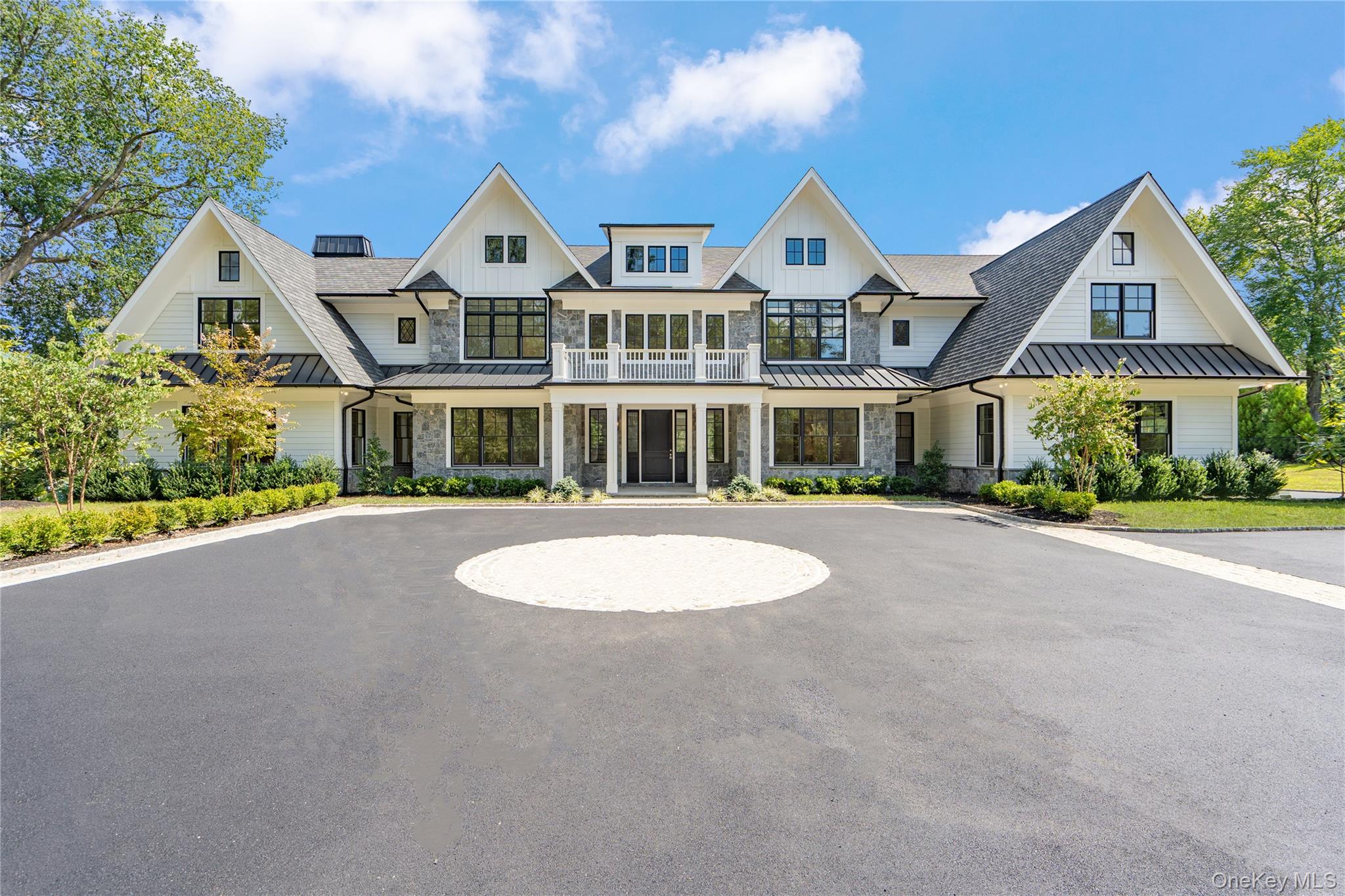 Brookville | An immaculate modern colonial has made its debut in Brookville. Sitting on 2.57 acres and totaling over 8,600 sq.ft. of living space, welcome to 8 Dogwood Hill - a newly completed luxury residence located on a lengthy, picturesque street just off of Cedar Swamp Road. Beyond the stone pillar entrance at the end of the driveway are two courtyards with belgium block accents that lead to the home - featuring a sleek white exterior, complemented with stone accents and black windows.

Entering through the front door welcomes you into the lofty foyer, revealing an elegant staircase leading to the second floor, large coat closet and marble powder room, catering to guests. Hidden behind a translucent glass door off the formal living room is a truly breathtaking space - a den with airy, cathedral ceilings, creamy oak paneling, and centered around a marble-encased fireplace. Paired with a powder room, this den can be transformed into a cozy retreat or private office space. Adding to the open-concept flow of the first floor, the formal living room leads to a spacious family room with a second marble fireplace, breakfast nook and the heart of the home - a custom chef’s kitchen. Complete with a waterfall marble island, white oak cabinetry, paneled dual dishwashers and Sub-Zero refrigerator & freezer, envision everyday meals, holiday gatherings, and hosted parties in this aesthetic and inviting atmosphere. Off the kitchen is a galley-style butler’s pantry providing extra storage and a wet bar, leading to the formal dining room. 

Thoughtfully curated for the modern lifestyle is an optimized service area, conveniently connecting the main living quarters to the rest of the home and property. The mudroom connects a back, side, and garage entrance to built-in storage, a hidden pantry, and access to all three floors via the backstaircase or elevator. Additionally, the first floor full bathroom is accessible via an outdoor entrance off the pool, and the first floor bedroom provides an excellent guest space or maid’s quarters. 

Making way upstairs and hidden behind double doors is a grand primary suite - offering an open bedroom and sitting area, separated by a double-sided marble fireplace. Just past the huge walk-in closet with build-in storage and island is a spa-like bathroom, with floor to ceiling marble tiling. Featuring a soaking tub with views of the front courtyard, double vanities and makeup station, the main highlight of possibly the entire home is a stunning, oversized walk-in shower. A rainfall showerhead is centered around steamers, body jets, and handhelds, with two benches, creating a tranquil escape to wash the day away. The second floor contains the remaining four bedrooms all feature en-suite full bathrooms and walk-in closets, full laundry room, and opportune bonus room with the potential to be transformed into a home office or play room. 

Outside, a 40’ x 20’ saltwater and heated gunite pool is surrounded by an expansive patio with outdoor kitchen, transforming the backyard into a private oasis. It also offers the opportunity to add personal amenities, such as a tennis/sports court or pool house, catering to your every need. The property features additional perks such as a full-home generator, central vac, radiant heat under all tile, smart home system, 3-car heated garage and an expansive lower level with outside access and potential to transform into a home gym/wellness center, media room, wine cellar or additional storage. 

Blending the Hamptons’ aesthetic and resort lifestyle with the prestige of Long Island’s North Shore—all while offering effortless access to New York City—8 Dogwood Hill embodies the very best of modern luxury living.