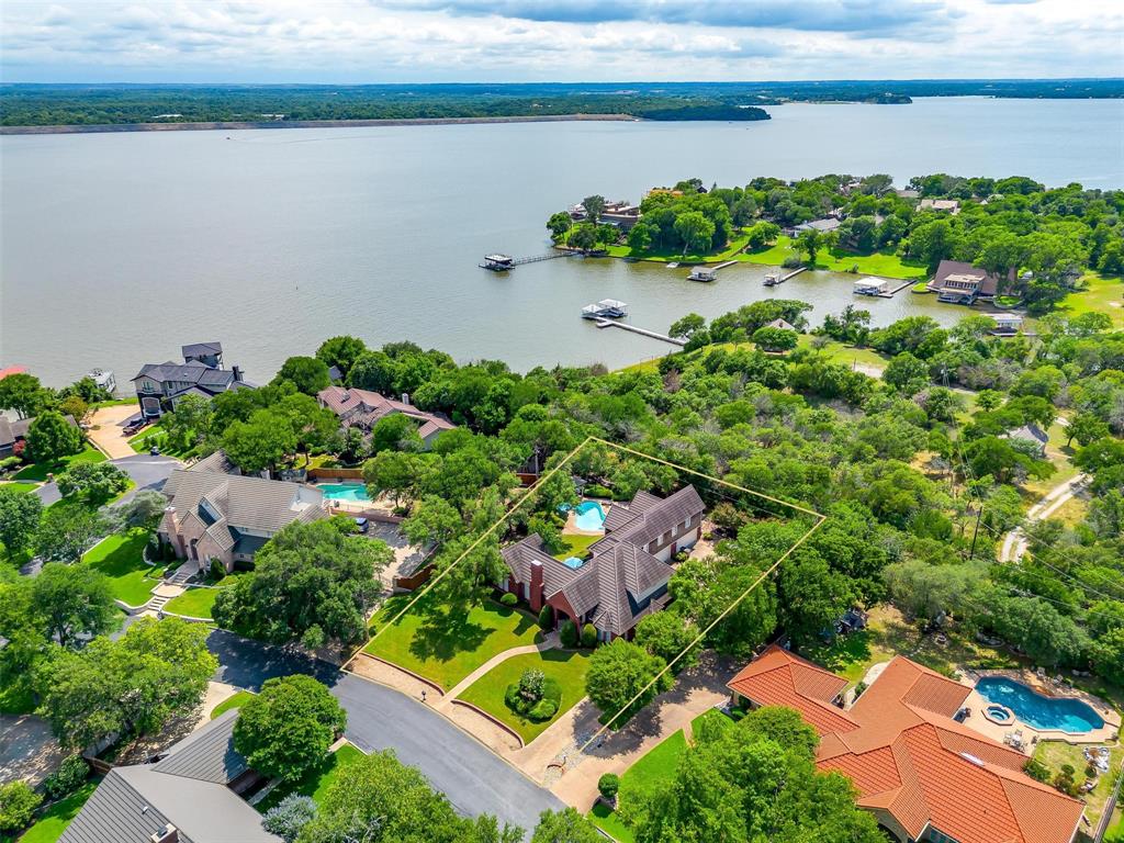 Nestled in the exclusive gated community of Crest Point, this French country-inspired custom home offers the rare combination of lake lifestyle, privacy, & luxury. Perfectly positioned just .3 mile from Lake Country Marina, you can zip down to the dock in your golf cart and be on the water in minutes. Whether it’s boating, jet skiing or kayaking, lake days are effortlessly within reach. Set on a mature, tree-covered lot that backs to a private, undeveloped acreage tract, the home’s crystal blue pool and spa feel like your own secluded resort. Enjoy serene mornings & quiet evenings in total privacy, surrounded by nature. With a 4-car garage and oversized driveway, there’s plenty of room for your vehicles, boat, water toys, and guests. Inside, the home is immaculately maintained with real oak flooring, abundant natural light, and thoughtful custom touches throughout. The main floor features a bright and spacious living area, dining room, and a beautifully appointed office with vaulted ceilings, built-in bookcase, and a dry bar with leaded glass details—an ideal work-from-home retreat. The kitchen includes granite countertops, stainless steel appliances, a cozy breakfast nook with built-ins, and bar seating for casual dining. A first-floor bedroom offers flexibility to serve as a secondary primary suite or private guest quarters. Upstairs, the primary suite is a true retreat with its own private staircase, a balcony overlooking the pool, and a peaceful atmosphere perfect for morning coffee. Two additional bedrooms and a large flex space—easily convertible to a fifth bedroom—complete the upper level. The home features a durable Class 4 slate roof. It is ideally located just 3 miles from the prestigious Fort Worth Boat Club and 4 miles from the scenic 400-acre Eagle Mountain Park, known for its nature trails and outdoor recreation. This is more than just a home—it’s a lifestyle on Eagle Mountain Lake. Come experience the perfect balance of lake living, luxury & privacy.