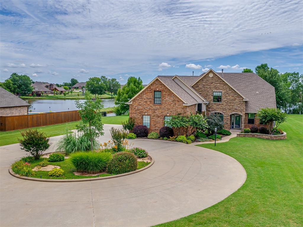 Discover serene lakeside living in this stunning home, situated on a 1.5 acre lot within the secure, gated Twin Lake community in Moore, and with a huge back patio spanning nearly the entire back of the home overlooking the lake.  A circle drive and a three-car garage provide an impressive welcome which continues with the fresh paint, new carpet, and fixtures throughout.  To the left of the entry, a formal dining room is brightened by a large arched window, with a cozy, double-sided gas fireplace, the other side of which is shared with the spacious living room.  Straight ahead is the the living room, featuring built-in surround sound speakers and large sliding glass doors that not only offer picturesque lake views but also provide direct access to the incredible back patio.  The living area is partially open to the kitchen, with a pass-through opening from the kitchen to the living room, and is completely visible from the breakfast area.  The kitchen is thoughtfully laid out for efficiency, with granite counters & island, and custom maple cabinetry with pull-outs, and with double ovens and a 5 burner gas cooktop this kitchen could host meals for one or everyone alike. Just outside the master is a coffee/wine bar complete with a wine fridge and the master itself features a tray ceiling and serene lake views and has a spa-like ensuite bathroom with heated tile floors, a large jetted tub, a separate tiled shower with dual showerheads, and a double vanity with leathered granite, and a generous closet with a built-in floor safe. The main level also includes two additional bedrooms, one of which could be perfect for use as study, and a full bathroom between them with a 36” door, well suited for any potential accessibility needs of family or guests. Upstairs, is a huge 285 sq ft bonus room, two more large bedrooms with walk-in closets, and a third full bath. For peace of mind, the house is generator-ready and has an in-ground storm shelter in the garage.