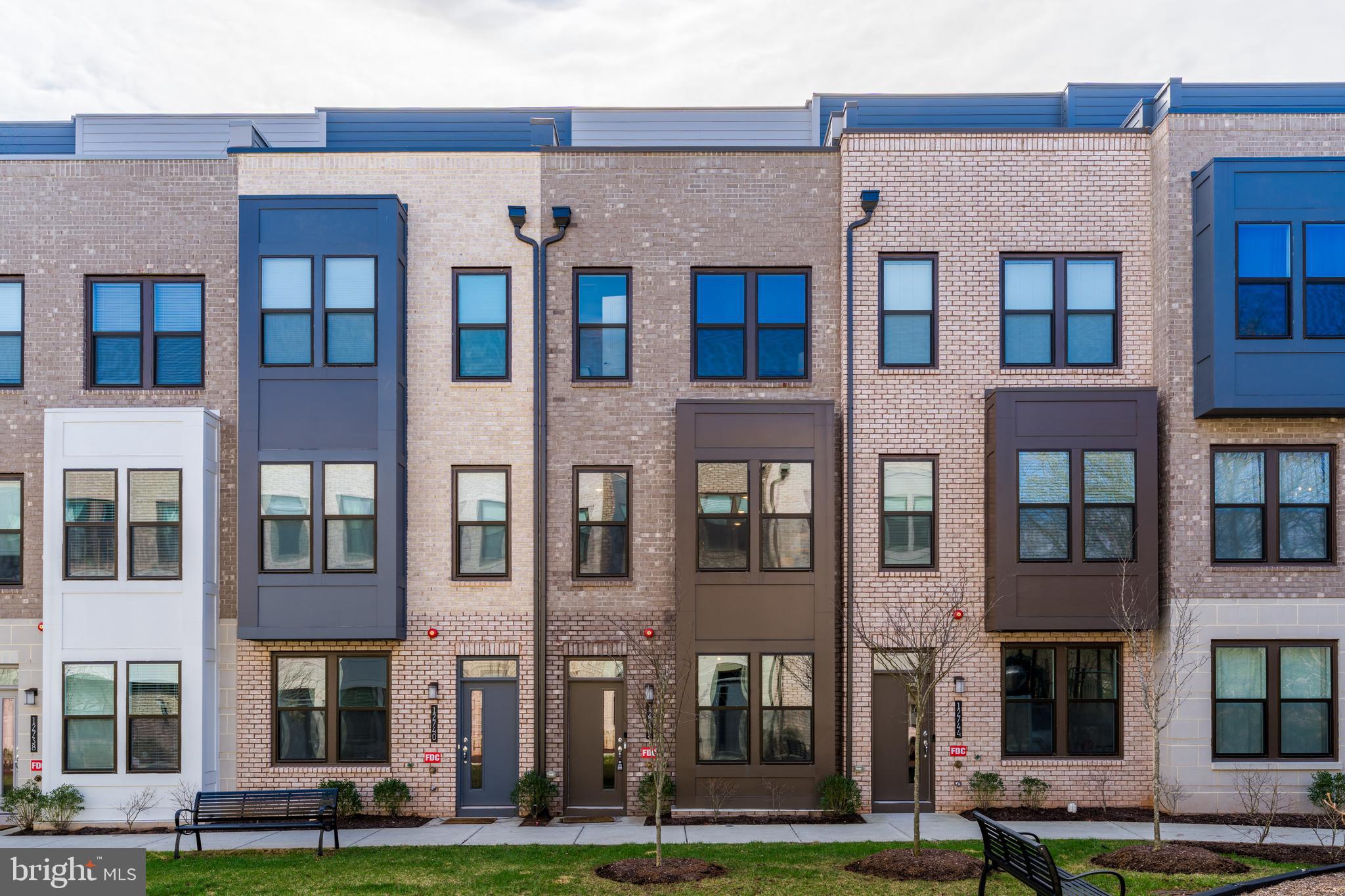Located in Reston Arboretum, one of the area’s newest townhouse communities, this three-bedroom, three-and-a-half bath home is just a six-minute walk to the Herndon–Reston East Metro, offering easy access to Dulles Airport, Tysons, Arlington, and downtown DC while maintaining a peaceful residential setting. The main level features a beautifully designed kitchen with a 10-foot waterfall quartz island with seating for four, soft-close gray cabinetry, stainless steel appliances, pendant lighting, and a pantry. The open layout flows seamlessly into the dining area and a light-filled family room with large windows and a sleek linear gas fireplace. Upstairs, the primary suite includes a walk-in closet and a spa-style bath with dual quartz vanities and a glass-enclosed shower with built-in seat, while a second bedroom offers its own en-suite bath. The top floor provides added flexibility with a loft ideal for a home office, lounge, or workout space, along with a third bedroom featuring a walk-in closet and private bath. The rooftop deck is a standout feature, offering peaceful tree views and a second linear gas fireplace—perfect for relaxing or entertaining. Additional highlights include neutral LVP flooring, recessed lighting, Schlage touchless keypads, energy-efficient systems, smart home features, and a tandem two-car garage pre-wired for an EV charger. Community amenities include green space, a playground, and dog-walking areas, with the Herndon Monroe Wetland Preserve just steps away. Reston Town Center is only three miles away, with shopping, dining, Whole Foods, the W&OD Trail, and convenient access to the Dulles Toll Road, Route 7, and Route 28. As part of Reston Association, residents enjoy access to pools, trails, parks, lakes, tennis and pickleball courts, and year-round community events.
