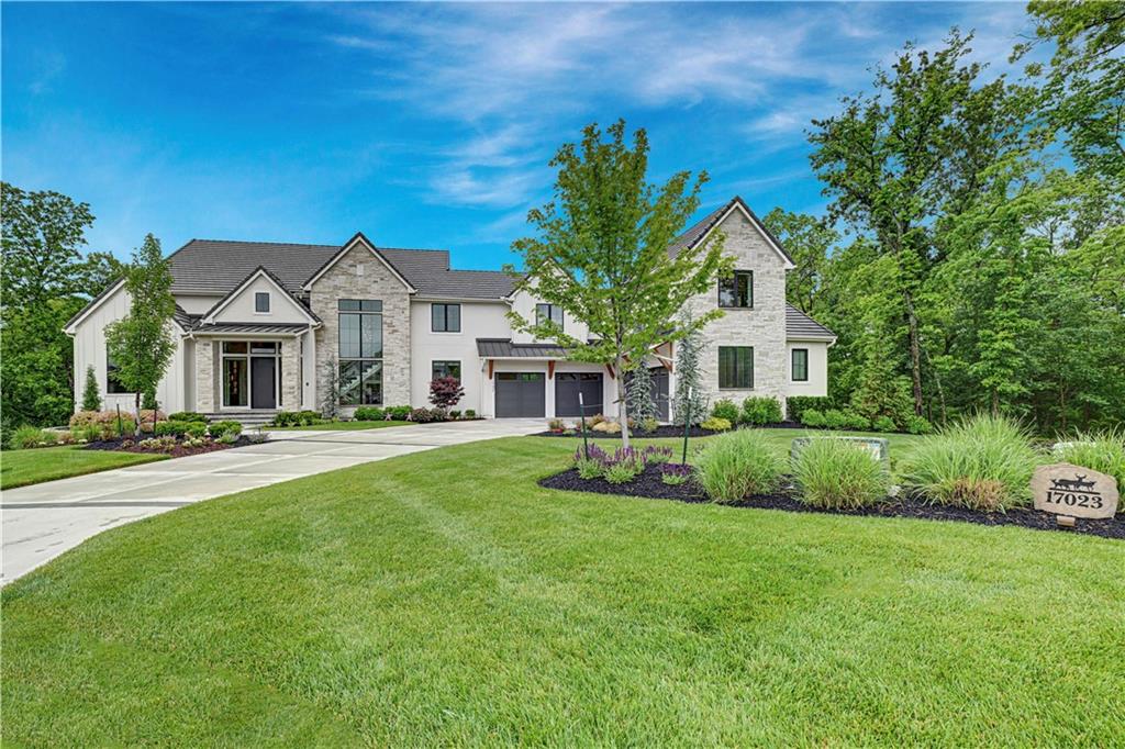 Skip the timeline of building and step directly into perfection with this 2-year-old custom masterpiece. Nestled on a nearly 1-acre, thickly treed cul-de-sac lot within the private, gated lake community of Loch Lloyd, this breathtaking 6,801 sq ft, 1.5-story estate blends luxury, convenience, and comfort.Professionally designed and styled with exquisite upgrades throughout, the home boasts rich Farrow & Ball paint colors, extensive trimwork, feature walls, designer wallpaper, custom electronic blinds throughout, & elite light fixtures. The vaulted gourmet kitchen is a chef's dream, features a massive quartz waterfall island and is open to the dining area with built-in buffet. A back kitchen is equipped with a second oven and dishwasher, and is perfect for entertaining. The dining room area includes a sophisticated bi-level bar and flows seamlessly into the hearth room, where vaulted ceilings, custom underlit shelving, a cozy fireplace, and a wall of glass frame the serene wooded views. Relax in the four seasons room with fireplace or work from the main-level office, complete with a feature wall, built-ins, and a third fireplace.The main-floor primary suite is a private sanctuary with a spa-like bath featuring underlit cabinetry, heated floors, cove lighting, marble accent wall, zero-entry dual shower, and a spacious closet with custom built-ins. Convenience is unmatched with laundry rooms on all three levels and a large drop zone off the 4-car (plus 2 golf car spaces) garage with epoxy floors.Upstairs is a versatile loft and 2 bedrooms with full baths. The walk-out lower level is an entertainer's paradise: a large rec/media room with surround sound, chic bar, guest suite, full gym, sauna, and steam shower. Outdoor living is easy with a composite deck, pavered patio, and fire pit. There's even a custom dog run with turf and a pergola. This is a rare, turn-key sanctuary crafted for the discerning buyer who demands effortless luxury.