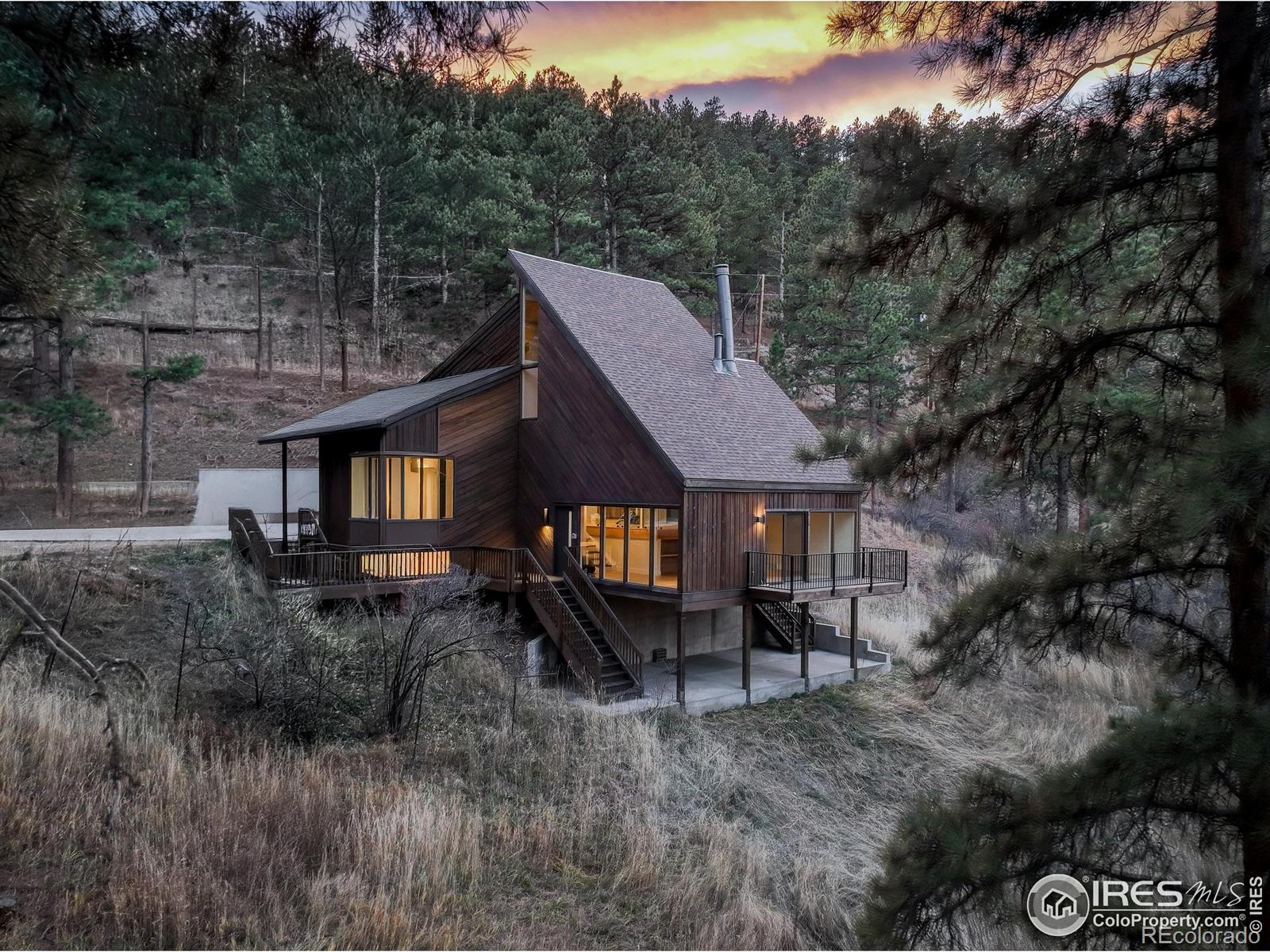 Welcome to this one-of-a-kind retreat nestled in Boulder's coveted Pine Brook Hills. Located just minutes from downtown yet tucked among mature pines and rocky hillsides, 1138 Timber Ln delivers the perfect blend of Colorado lifestyle and architectural distinction. From the dramatic exterior lines and generous glazing to the warm natural materials throughout, this home embodies style and setting in equal measure. Meticulously updated, the home features a new roof, fresh interior paint, new flooring, beautifully remodeled bathrooms, and a brand-new kitchen that blends modern design with mountain warmth. The open stairway with sleek glass railings adds a contemporary architectural touch and enhances the home's light-filled, airy feel. The open living area showcases panoramic windows framing the surrounding woodland, while the private primary suite provides a peaceful retreat. Set on approximately 1.1 acres, the property offers both seclusion and opportunity-enjoy morning coffee or evening stargazing from one of the many decks, surrounded by nature yet just minutes to Pearl Street, downtown Boulder, and nearby trailheads. With 3 bedrooms, an office or flexible living space, 2.5 baths, and an attached garage, this home combines architectural character, modern comfort, and a true "away-from-it-all" feel. A rare opportunity to own a stylish, private retreat perfectly at home in the pines.