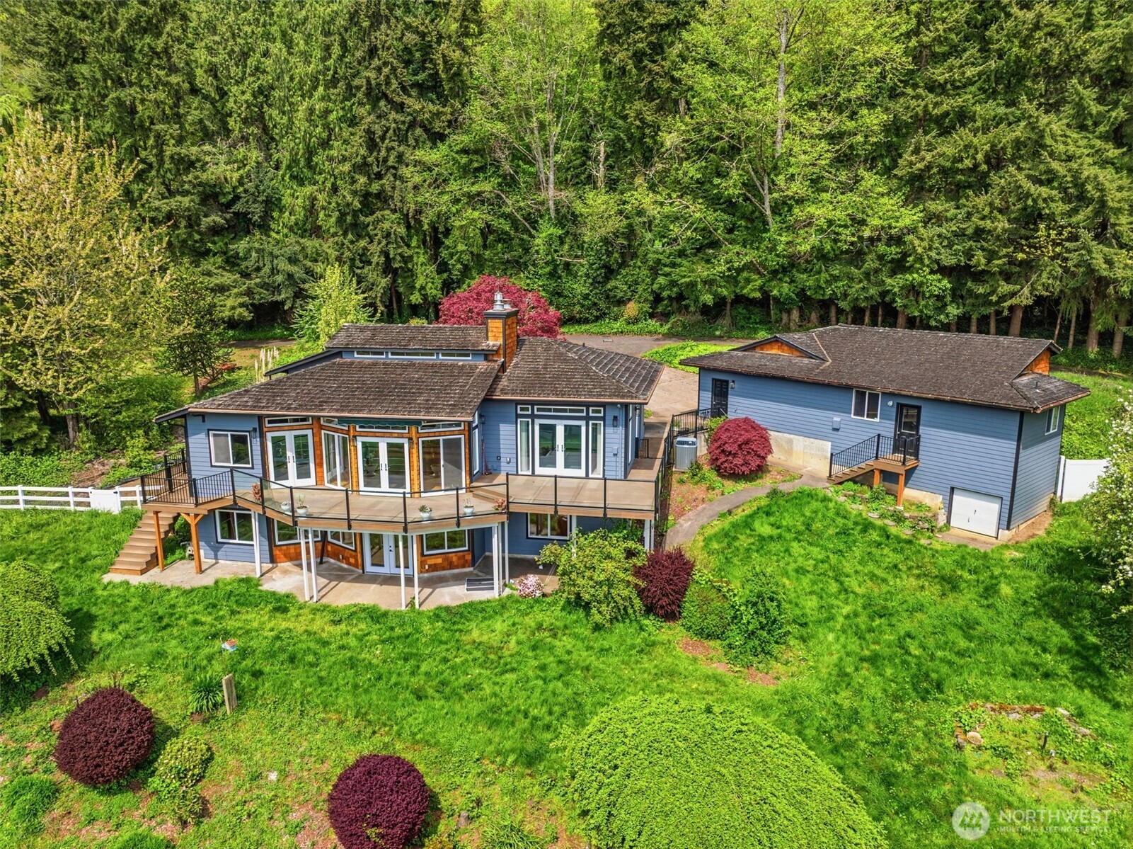 Perched above the Columbia River with a truly spectacular, sweeping view, this beautifully crafted 2,845-square-foot home offers Northwest living at its finest. Set on a private 1-acre parcel, the property blends timeless craftsmanship with an exceptional sense of space, light, and serenity. Inside, cherry-inlaid hardwood floors and rich wood plank ceilings create an atmosphere of warmth and elegance. Multiple sets of French doors open to an expansive deck that spans the back of the home—perfect for entertaining, relaxing, or simply taking in the stunning river vistas. Both the living room and the primary suite are positioned to capture the panoramic views, making every day feel like a retreat. The detached three-car garage provides abundant storage and flexibility, complete with an interior garage door that leads to a very large, dedicated shop area at the rear—ideal for hobbies, projects, or additional workspace.