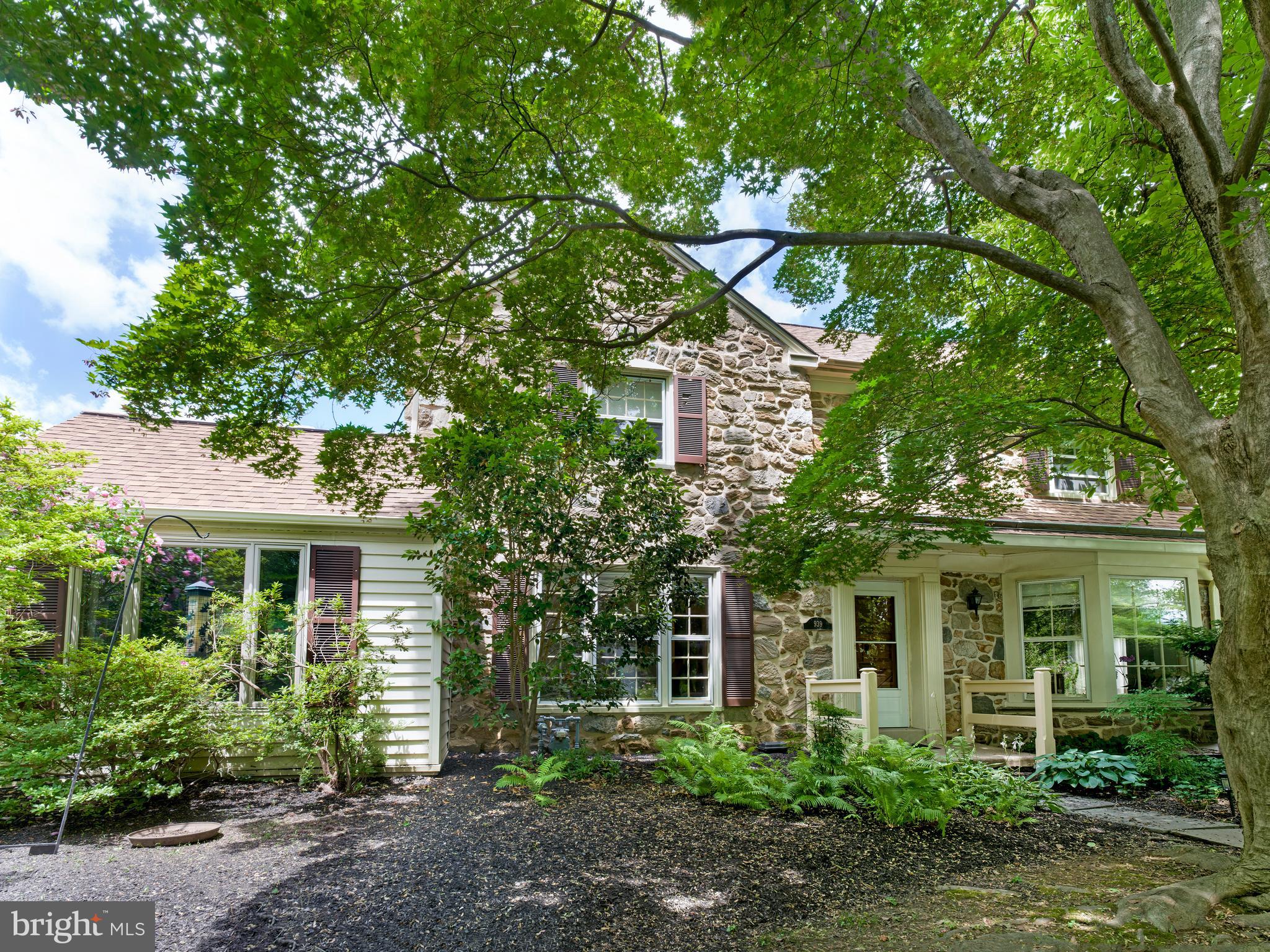 Open House Canceled Sat July 25. Located in the coveted Shortridge Tract of Wynnewood, this classic stone Colonial is surrounded by mature specimen trees, lush gardens, and a charming covered front porch, creating a private and picturesque setting on a beautifully landscaped .19-acre lot. Offering 3 bedrooms, 2 full baths, a powder room, central air, gas heat, an attached two-car garage, and a partially finished basement, the home blends timeless character with thoughtful updates. A welcoming center hall foyer introduces gracious, light-filled rooms with hardwood floors throughout much of the first floor. The spacious living room features a fireplace, custom built-ins, and large windows overlooking the gardens. Just beyond, a sun room with a stone accent wall provides the perfect space for relaxation.  The walls of windows overlooking the gardens offers a peaceful place to enjoy the changing seasons.The formal dining room, highlighted by a beautiful bay window, provides an elegant setting for entertaining and everyday meals. The updated kitchen features granite countertops, stainless steel appliances, abundant cabinetry, and convenient access to the rear yard. A powder room completes the first floor.The second level offers a spacious primary suite with a private bath, while two additional generously sized bedrooms share a hall bath. A large walk-up attic provides exceptional storage and potential for future expansion.The partially finished lower level offers flexible space for a recreation room, exercise area, or playroom, while the unfinished area provides abundant storage.Ideally located within the award-winning Lower Merion School District, this exceptional home is just moments from Shortridge Memorial Park, Wynnewood Valley Park, Suburban Square, regional rail service, and Center City Philadelphia. A rare opportunity to own a beautifully maintained stone Colonial in one of Wynnewood’s most desirable neighborhoods.