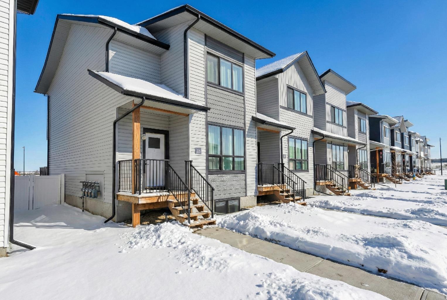 END UNIT with A/C and March 1 possession available. Stylish, spacious, and modern 2-storey townhome in the new community of Iron Gate, offering low-maintenance living and peace of mind with Alberta New Home Warranty still in place. Enjoy your charming 7' x 7' front deck before entering a bright, open-concept main floor filled with natural light from large energy-efficient triple-pane windows. Durable vinyl plank flooring runs throughout the main level, while plush carpet upstairs adds warmth and comfort.The kitchen truly anchors the home with a massive island featuring extended quartz countertops, perfect for stools, homework time, or late-night chats, plus a built-in pantry and four stainless steel appliances. The expansive dining area easily accommodates a full-size table with room to host, and the separate mudroom with a half bath offers practical family functionality with direct access to the east-facing back deck. Outside, enjoy a fully fenced backyard with rear lane access, two parking stalls, and space for a future single detached garage.Upstairs includes a convenient laundry room, two generously sized bedrooms, a full main bathroom, and a primary suite complete with a walk-in closet and 4-piece ensuite. Extra-large hallway closets provide excellent additional storage. The basement is unfinished and ready for your ideas, already plumbed and framed for a future bedroom, bathroom, and rec room, with large windows bringing in great natural light. Central A/C keeps the interior comfortable year-round.Located close to shopping, restaurants, and Highway 20 for quick access in and out of town, this move-in-ready home checks all the boxes for comfort, convenience, and long-term value.