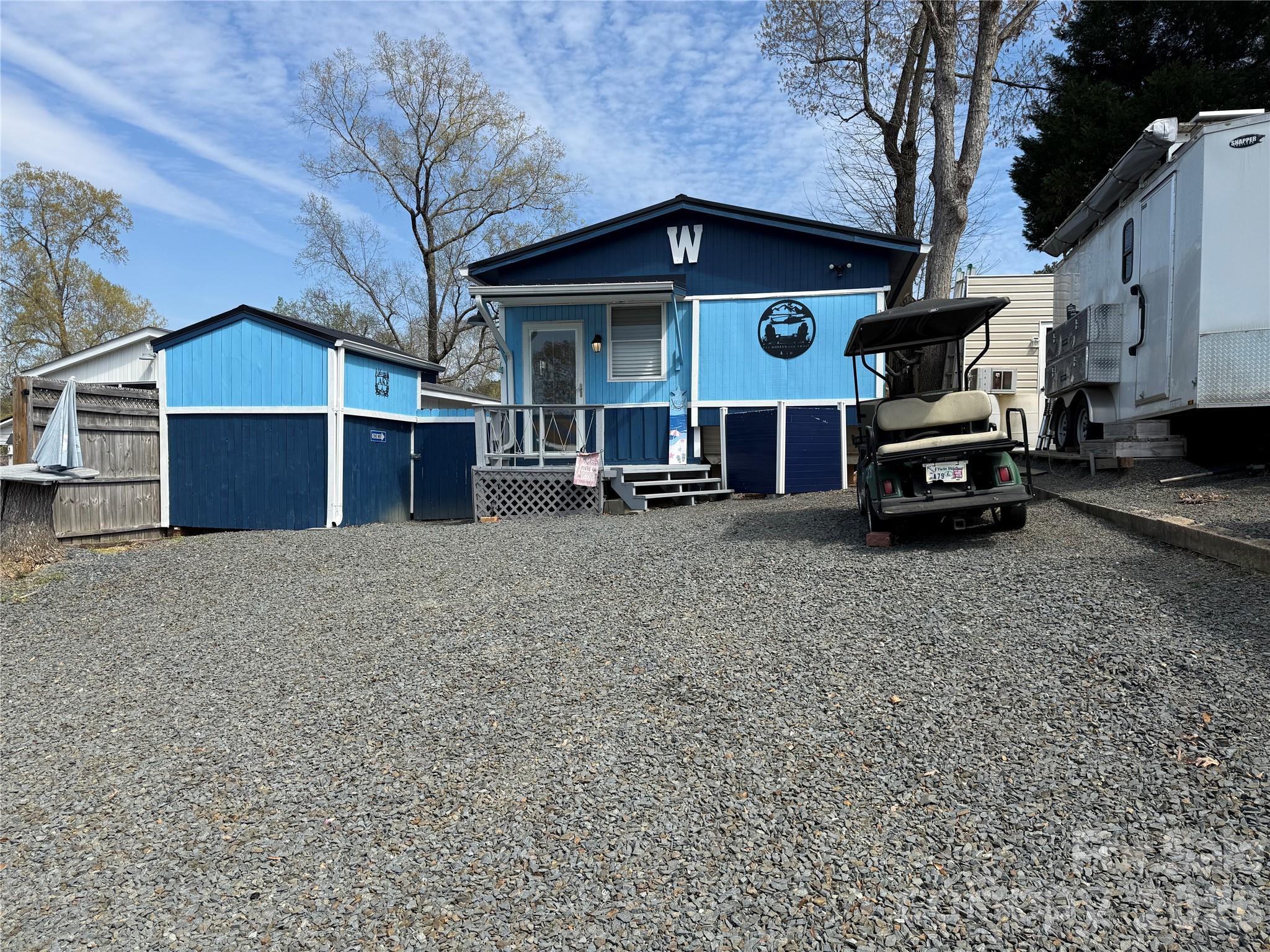 Welcome to this unique unit here in the park. This a 2 bedroom, 2 1/2 baths unit with a fabulous outdoor kitchen setup and a second sleeping/bathroom space. Included in the outdoor kitchen -  Blackstone Gas Griddle, Blackstone Prep Area, covered with elec and fan. Move over to the covered bar side and you have 4 stools, a beverage refrigerator, Microwave, Ninja Foodie Grill, Panini Maker, Oster French Door Oven. Power and a TV are already there. There is a covered swing, fenced yard for the pets and a pet washing station. Inside is a great living room freshly painted with new flooring. Most furnishing to remain. U shaped couch makes a comfortable queen bed. The kitchen has an ice maker, great counter space and brand new flooring. Metal roof is 1 year old. Propane Hot Water on Demand 2 years old. 2 Window units for AC and a wall mounted propane heater for your heat source. Access door just added to the side of unit for the convenience of letting the dogs out into the fenced area. Full bath with walk in shower. Storage or Sleeping loft above main bath room. Double size bed and 1/2 bath on the camper side. Out back is double bunks, a full bath and enough room to add a washer and dryer if desired. Portable A/C and fan.Come and see if this is your "Happy Place" here in the Park. No title to camper, Bill of Sale will be provided. There are 2 Yamaha 2011 golf carts available for Alum wheels $4k, black wheels $3k. All buyers must be with a realtor to gain access to the community.