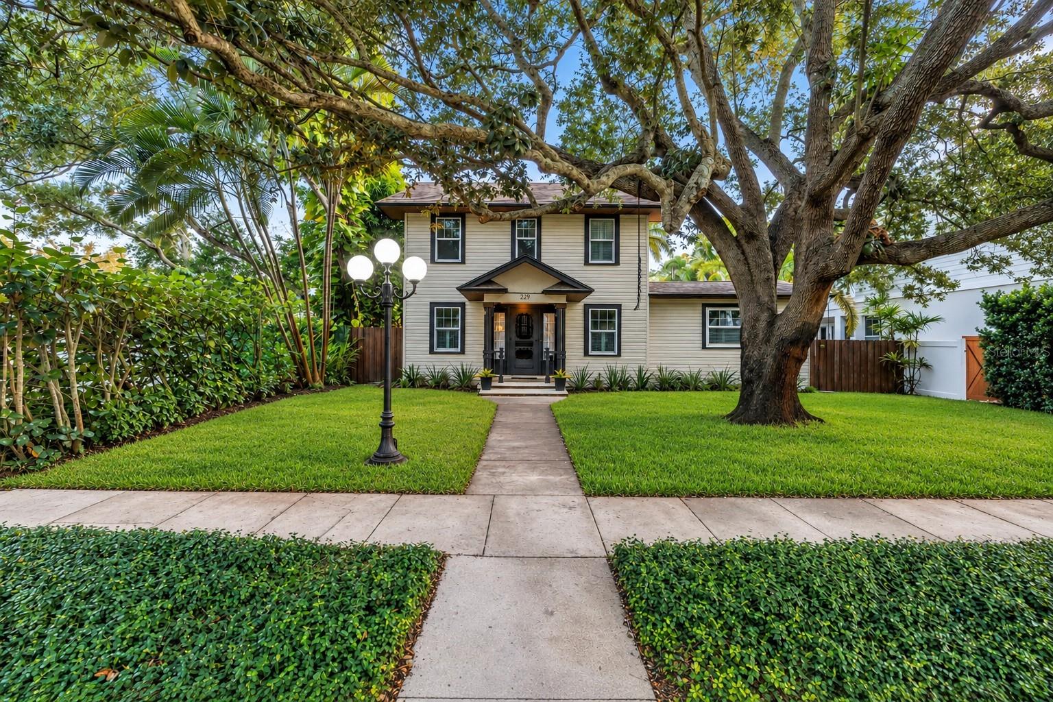 Gorgeous Old Northeast home blending timeless 1920s character, chic updates, and an exceptional outdoor oasis. The main home offers 4 bedrooms, 3 full baths, and a versatile 3rd-floor bonus room. A detached ADU features an air-conditioned game room plus a legal 1-bedroom, 1-bath upstairs apartment with its own kitchen, laundry, parking pad, and separate access—ideal for guests, extended family, or rental income. Enter the light-filled main home to find original hardwood floors, beautiful moldings, and a striking decorative fireplace. An elegant archway connects the living and dining rooms. The 2024 custom chef’s kitchen features black wood cabinetry, imported brass hardware, black stainless appliances, Kraus Onyx granite sink with touchless brass faucet, built-in pantry, custom spice cabinet, and a gas 5-burner ILVE dual-fuel range. Dolomite countertops, a bookmark slab backsplash, floating walnut shelves, and an eat-in banquette with 5 storage drawers and custom walnut table add style and function. The wine and coffee bar includes gold glass tile, walnut shelving, Sharp drawer microwave, dual-zone wine cooler, appliance garage, and additional storage. A fun full guest bath with Florida orange wallpaper, hex tile, and Rejuvenation fixtures doubles as a pool bath just inside the French doors. The downstairs primary suite features a coffered ceiling, built-in closet, and en-suite bath with marble basket-weave and subway tile and chrome Kohler fixtures. Upstairs are 3 additional bedrooms with abundant natural light and closet space, plus a full bath remodeled in 2025 with birch double vanities, recessed medicine cabinets, and restored original mosaic floor. A second-floor laundry room adds convenience and storage. The 3rd-floor bonus room offers wood floors and custom built-ins, perfect for a playroom, office, guest space, or additional bedroom. Outside, the expansive travertine-pavered lanai provides plenty of room for entertaining. The large saltwater pool was refinished in 2019 with a PebbleTec finish and features a sun shelf and deep-water bench. A fire-pit area completes the outdoor retreat. The ADU’s lower level includes a large storage room for bikes, tools, lawn equipment, holiday décor, and outdoor furnishings, plus an air-conditioned game room with ping pong table, TV mount, seating, and storage. Upstairs, the legal 1-bedroom, 1-bath apartment features original hardwood floors, living and dining areas, granite kitchen with white cabinetry and Anthropologie fixtures, renovated bath, newer mini-split HVAC units, dedicated laundry, and a spacious bedroom with built-in closet and abundant natural light. Located in the heart of the Old Northeast and not in a flood zone, with convenient access to downtown St. Petersburg, Coffee Pot Bayou, 4th Street shops and restaurants, and I-275. A rare opportunity combining historic charm, modern updates, resort-style outdoor living, and a flexible ADU ready for its next owner!