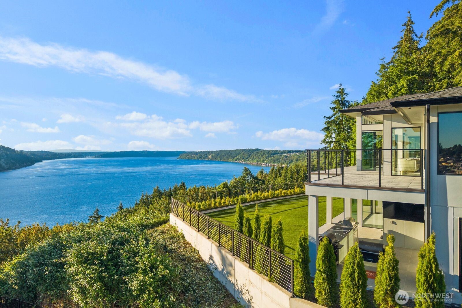 Experience the pinnacle of luxury living from this private, gated estate set on 1.5 acres with sweeping views of the Tacoma Narrows Bridges, Gig Harbor, and the Olympic Mountains. Designed for flexibility and entertainment, the home features two fully functioning levels, each with its own kitchen, primary suite, living room, and laundry room – ideal for multigenerational living, extended guests, or seamless everyday comfort. The outdoor entertainment spaces are highlighted by a 1,400+ square foot view deck and an equally sized heated patio on the daylight basement level complete with an outdoor bar. Whether hosting large gatherings or enjoying a quiet evening, the multiple outdoor living areas take full advantage of the home's stunning surroundings. A private putting green adds to the resort-style experience, while the expansive grounds provide a rare sense of privacy and seclusion. For vehicle enthusiasts, the gated elevated driveway delivers an unparalleled sense of arrival as you crest the driveway and secure your vehicle in one of the four garage bays. There is more than enough driveway parking for guests when you use the entertainment capabilities of this property to its fullest. Offering a combination of luxury, versatility, and unmatched views, this exceptional property is one of Tacoma's most luxurious residential offerings. An additional 2.5 acres is available for purchase separately, creating a rare opportunity to expand the estate or preserve even greater privacy.