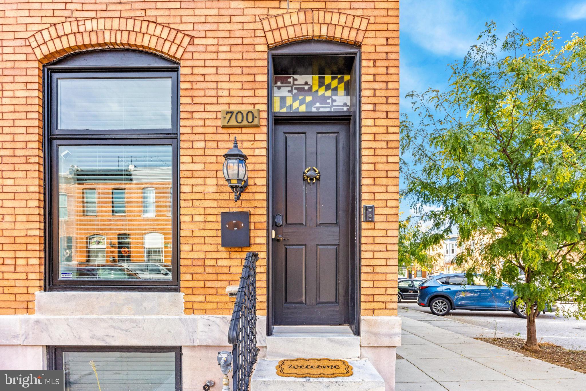 The Canton trifecta: a rooftop deck with downtown skyline views, an attached garage, and Patterson Park two blocks from your front door. This brick end of group was gut renovated in 2014, and sitting at the end of the row gives you windows on three sides and the kind of light that’s hard to find in a city rowhome. Inside, the main level runs long and open, with an exposed brick wall from front to back, crown molding, recessed lighting, and hardwood floors throughout. A few steps up at the rear, the kitchen has white shaker cabinetry, dark granite, stainless appliances including a gas range, and windows on two sides, with an open rail that keeps the cook in the conversation. Upstairs, the primary suite has four windows, a walk-in closet with built-in shelving, and a bath with two separate vanities and a marble-tiled walk-in shower with a rain head. The second bedroom has its own wall of exposed brick and a double closet, with a second full bath just down the hall. The finished lower level adds a third bedroom and full bath for guests, a home office, or a roommate. Then there’s the garage: pull straight in, carry the groceries up, and skip the nightly lap around the block. Mornings start with coffee at OneDo Coffee Roasters a few blocks away or the crab dip bagel at Café Dear Leon on O’Donnell Square. And when the day winds down, head up to the roof deck, where the downtown skyline fills one side of the view and the Patterson Park treeline fills the other, best enjoyed on a cool fall evening.
