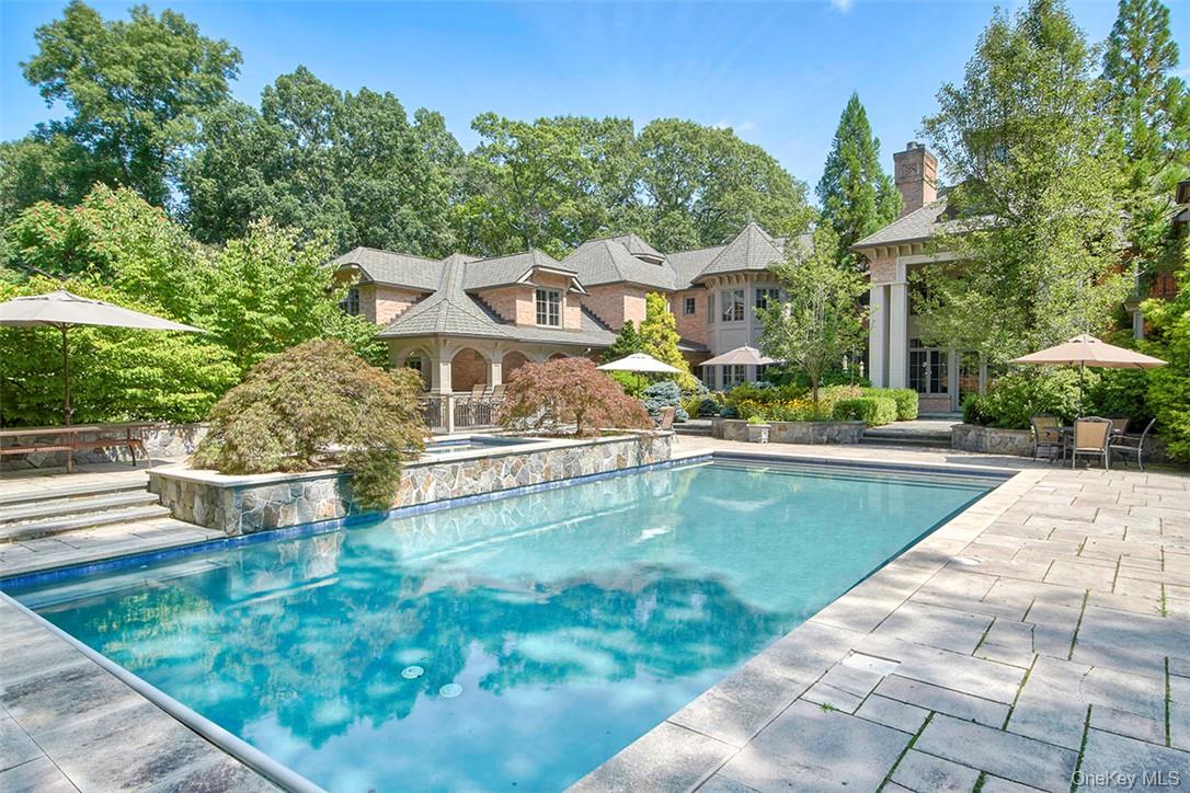 Timeless elegance meets exceptional craftsmanship in this spectacular brick and stone estate, privately set behind gates on 4+ acres in one of Chappaqua's prestigious Whippoorwill neighborhoods. Designed by acclaimed architect Carol Kurth and masterfully built in 2003 by renowned builder Robert Torre, this extraordinary 5-bedroom, 6 full, 1 half bath residence offers over 10,000 square feet of impeccably crafted living space, where timeless architecture, luxurious finishes, and modern comfort come together seamlessly. A long private drive leads to a grand arrival. Inside, a dramatic two-story foyer with a sweeping circular staircase sets the tone for the home's impressive scale and refined design. Every room features soaring 10-ft ceilings, while the entry foyer and formal living room rise to over 20 feet, filling the home with light and volume. Rich hardwood floors, exquisite custom millwork, recessed lighting, and four fireplaces enhance the warmth and sophistication throughout. Designed for both grand entertaining and comfortable everyday living, the main level flows effortlessly from room to room. A spectacular formal living room with walls of windows opens to a gracious dining room, while the designer chef's kitchen features custom cabinetry, honed natural limestone floors, an oversized island with seating, breakfast area, abundant prep space, and premium stainless appliances including a 48" Wolf range, 30" Wolf convection oven, Thermador microwave, separate 36" Sub-Zero refrigerator and freezer, and 2 Bosch dishwashers. A butler's pantry enhances entertaining, and French doors lead to an expansive stone terrace overlooking the pool and grounds. Adjacent to the kitchen, the family room is anchored by a striking stone fireplace. The 1st floor also includes a spacious guest suite with a private bath, a back hall with pool bath, and access to the heated epoxy-finished three-car garage with room for up to five vehicles using lifts—a dream for the automobile enthusiast. Between 1st and 2nd floors is a private office and below a wine tasting room. The luxurious primary suite offers a dressing room, two oversized walk-in closets, a private balcony overlooking the backyard, and a spa-inspired bath with radiant heated floors, whirlpool tub, and steam shower. Three additional en-suite bedrooms, an expansive recreation room, and a 2nd floor laundry complete the upper level, while an additional 1st floor laundry room adds convenience. An enormous unfinished lower level offers exceptional potential for a home theater, fitness center, wine cellar, golf simulator, or additional recreation space. The outdoor setting is equally impressive. Beautifully landscaped grounds designed by acclaimed landscape architect Louis Fusco feature sprawling level lawns, specimen plantings, curated gardens, classic stone walls, and a magnificent Cardillo saltwater pool with a new filtration system and electric safety cover. An expansive stone patio and charming gazebo provide exceptional spaces for entertaining and relaxation. Bordering the Glazier Arboretum and backing to forever protected land, the property enjoys extraordinary privacy, tranquility, and picturesque natural surroundings. Additional amenities include a whole-house generator, electric vehicle charger, Elan smart home system for lighting, thermostats, and security. Just minutes from downtown Chappaqua, award-winning schools, and Metro-North for an approximately 50- minute commute to Manhattan, this remarkable Whippoorwill estate represents a rare opportunity to own one of Chappaqua's premier luxury properties.
