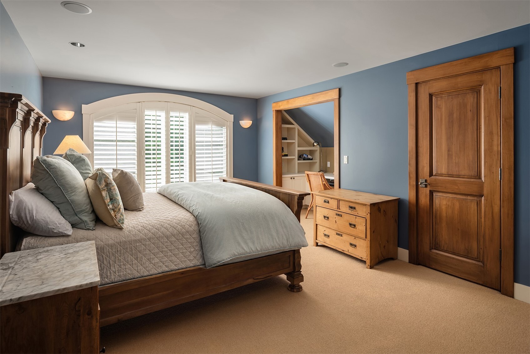 Blue bedroom with wood bed frame and built-in desk nook