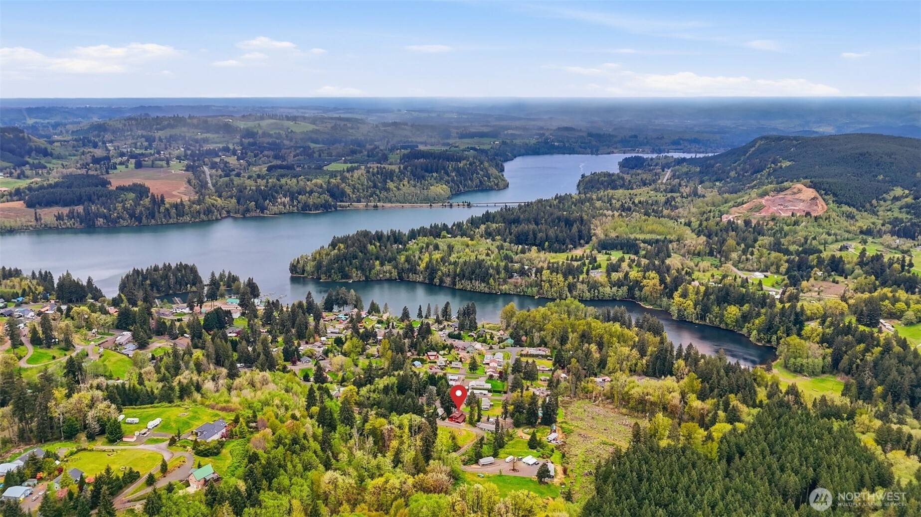 This is your opportunity to own a charming, turn-key home in the desirable Mayfield Lake Village area, paired with a rare 5+ acre lot just across the street. These two tax lots offer exceptional flexibility—live in the home as-is, expand, build, or hold as an investment in a location where opportunities like this are limited. Perched above surrounding hills & framed by evergreens, the home captures sweeping territorial & lake views, creating a peaceful retreat. Inside, you’ll find warm wood finishes, exposed beams, & expansive windows that bring the views front & center. The main living area features vaulted ceilings & a stunning Montana stone fireplace, while large sliders open to spacious decks—perfect for relaxing or entertaining. The layout includes multiple living spaces, with a lower level offering its own fireplace, ideal for guests or a private retreat. The kitchen is well-positioned with ample cabinetry & easy flow into the main living areas.  Major updates have already been completed, including electrical & plumbing improvements, a new roof & windows, updated flooring, fresh exterior paint, & rebuilt decks—making this home truly move-in ready. The additional acreage provides valuable space & future potential, with a cleared area offering territorial & peekaboo lake views. Utilities are already on site, making it ideal for expansion or recreation. Enjoy privacy & a serene setting just minutes from Mayfield Lake, with a marina & boat launch nearby.