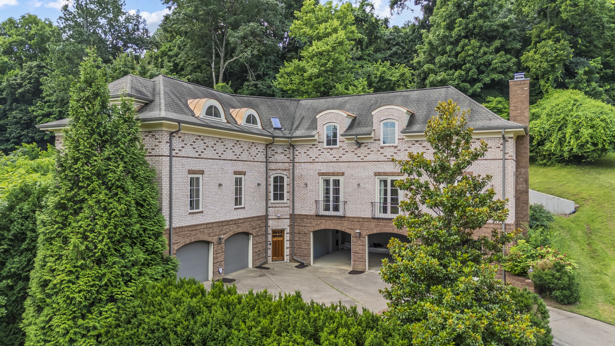 Experience timeless elegance in this custom-built, French chateau-inspired home, nestled in the prestigious Woods of West Meade. Spanning 4,921 sq ft across three beautifully finished levels—with the convenience of a private elevator—this estate offers the perfect blend of luxury, comfort, and modern convenience.  Designed with versatility and refinement in mind, the home features 5 spacious bedrooms, each with en-suite bathrooms and most with walk-in closets, plus 2 additional half baths. The first-floor guest suite includes its own private patio, perfect for extended stays or multi-generational living. Throughout the home, natural white oak flooring sets a warm, sophisticated tone.  The  kitchen is outfitted with granite countertops, Sub-Zero, Wolf, and Thermador appliances, and is complemented by matching granite surfaces in all bathrooms and the laundry room. Additional features include a recirculating hot water system, heated primary bathroom floor, central vacuum, intercom, security system, EV charger wiring, and a spacious 5-car garage.  Storage is abundant with two additional first-floor storage rooms off the garage, three oversized closets in the bonus room, and generous attic space. The bonus room offers incredible flexibility for a playroom, media space, or home office setup.  Step outside to enjoy a tranquil stone patio off the kitchen, ideal for morning coffee or al fresco dining, all while overlooking a peaceful backyard that backs to mature woods, offering both privacy and beauty.  Located just minutes from upscale shopping and  dining, this West Meade estate delivers exceptional craftsmanship, thoughtful design, and enduring style in one of Nashville’s most desirable neighborhoods.