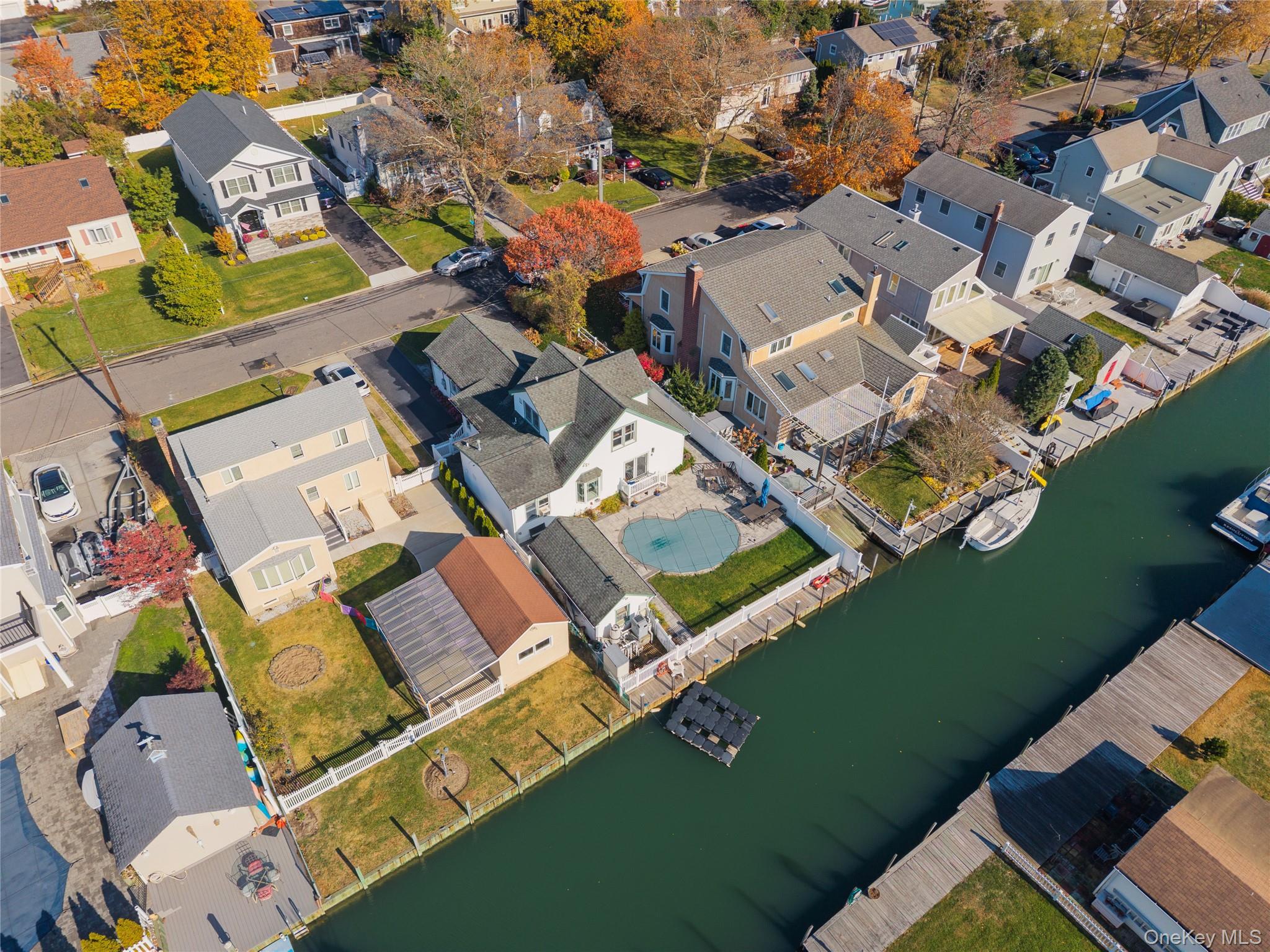 Experience life on the water in this beautifully updated expanded ranch tucked away in South Amityville’s coveted waterfront community. The open concept layout is light filled and welcoming, featuring vaulted ceilings, rich hardwood floors, and designer touches throughout. The living and dining areas flow effortlessly together, creating a perfect setting for everyday living and entertaining. The kitchen is both stylish and functional with granite counters, stainless appliances, and crisp white cabinetry that extends to the ceiling. It is perfect for entertaining and opens seamlessly to the main living space. Step outside to your private backyard retreat complete with a heated in ground gunite pool, paved patio for lounging or dining al fresco, and your own bulkhead with deep water canal access ideal for boating, paddleboarding, or simply soaking in the coastal lifestyle. A detached garage offers extra storage for all your toys and seasonal gear. This home combines modern comfort with timeless charm, offering year round vacation vibes just minutes from the village, local dining, and the Great South Bay.